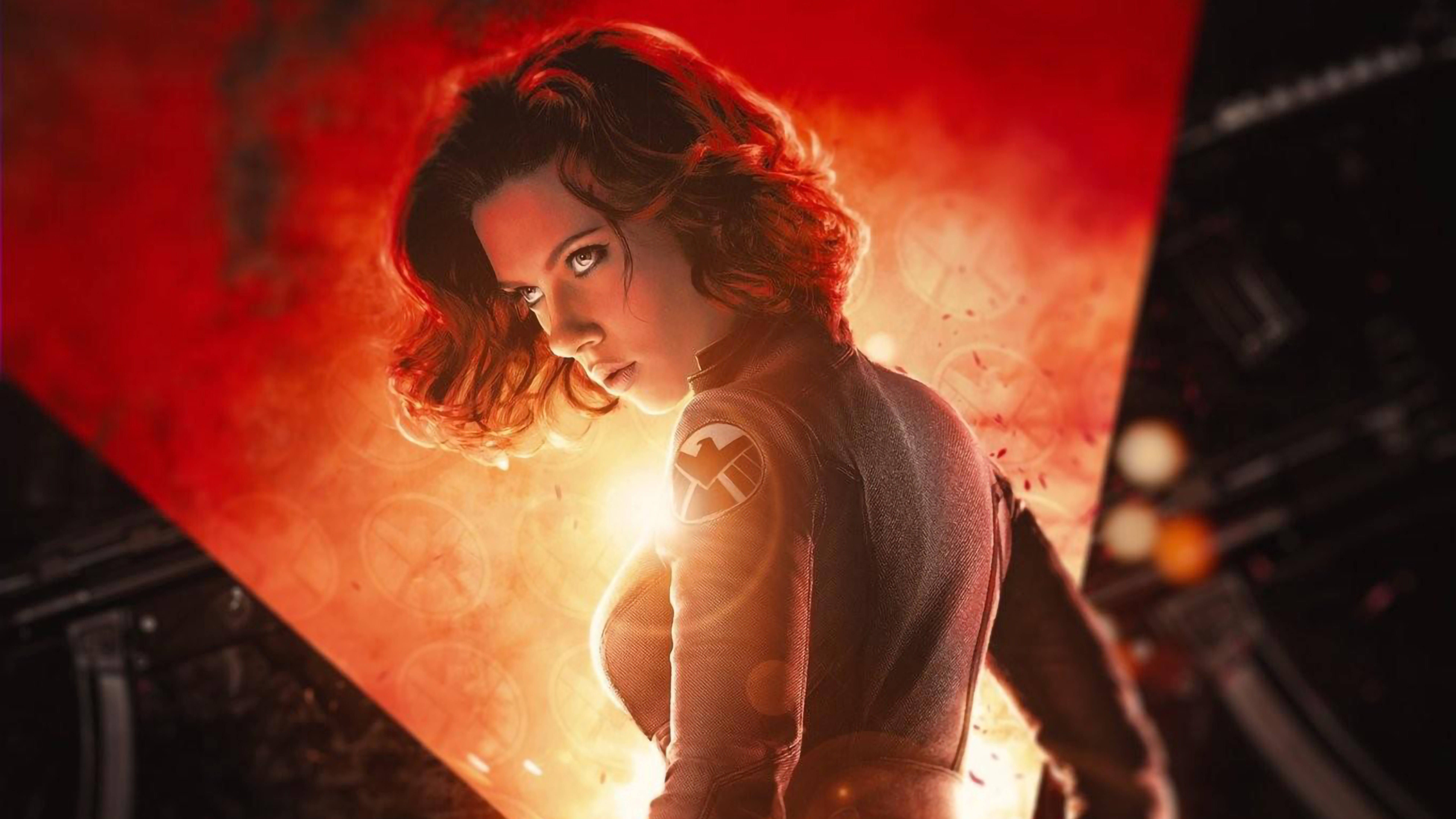Scarlett Johansson Black Widow 桌布 壁紙 — 一位紅髮的兇猛女性穿著帶有發光徽章的戰術服，站在戲劇性的火光中。