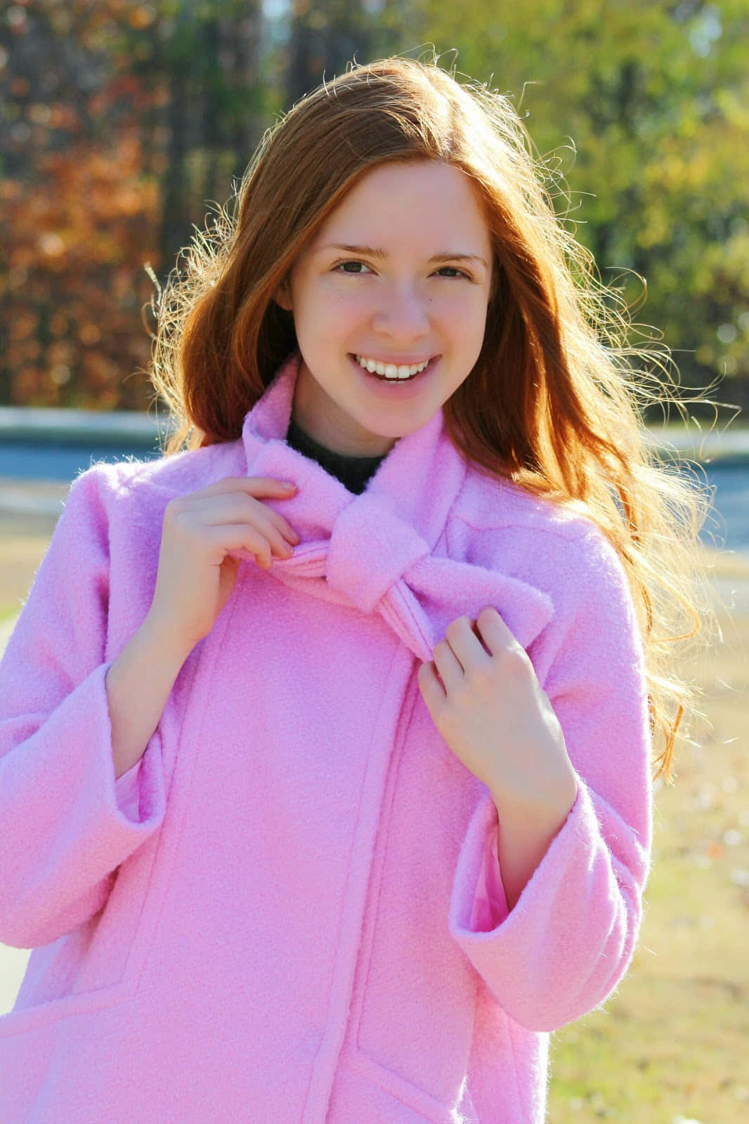Pink Coat 桌布 壁紙 — 一位紅髮的開朗年輕女性在秋天戶外調整她的亮粉色外套時溫暖地微笑。