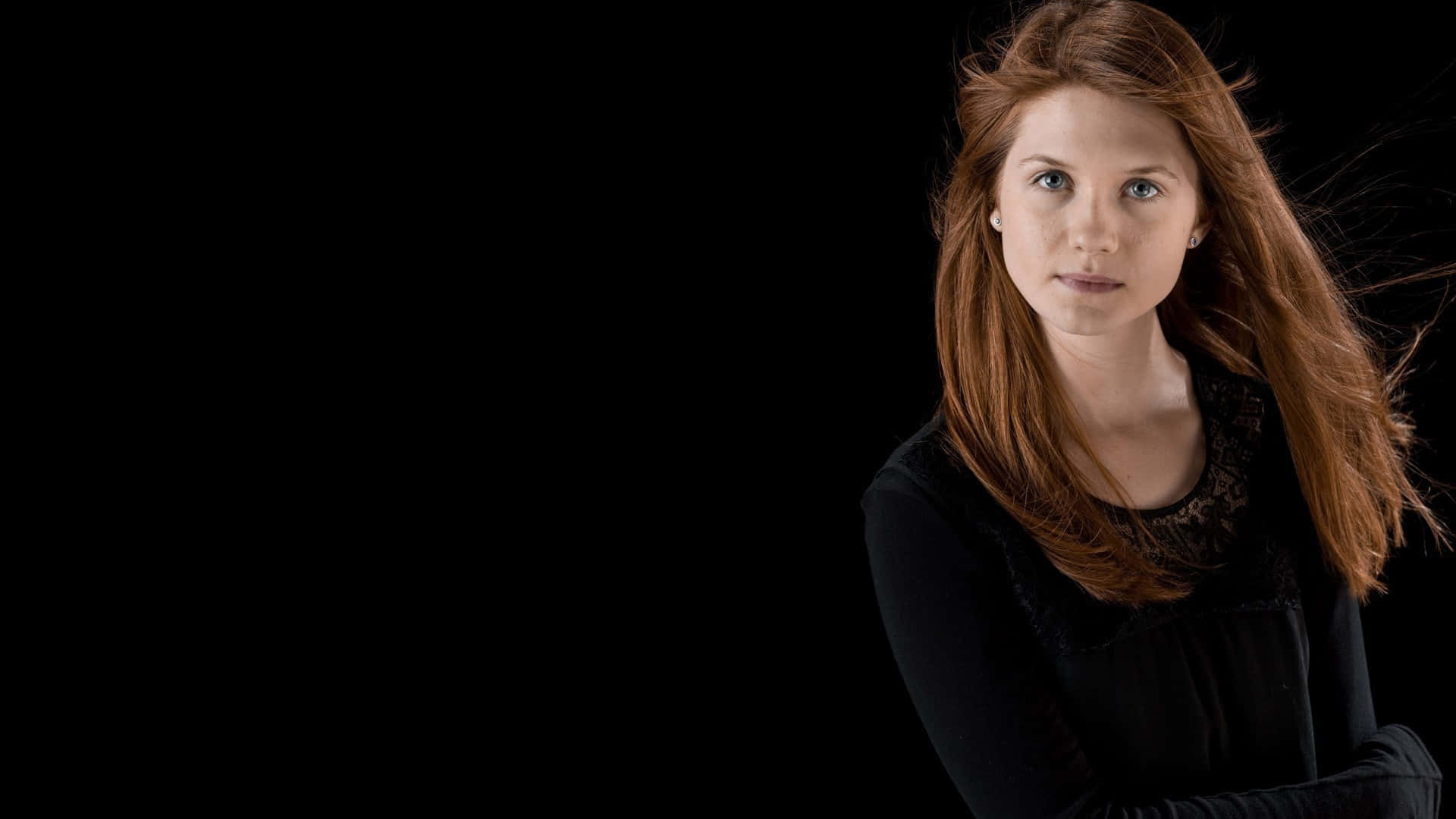 Ginny Weasley 桌布 壁紙 — 一位紅髮藍眼的女性在純黑背景下直視鏡頭。