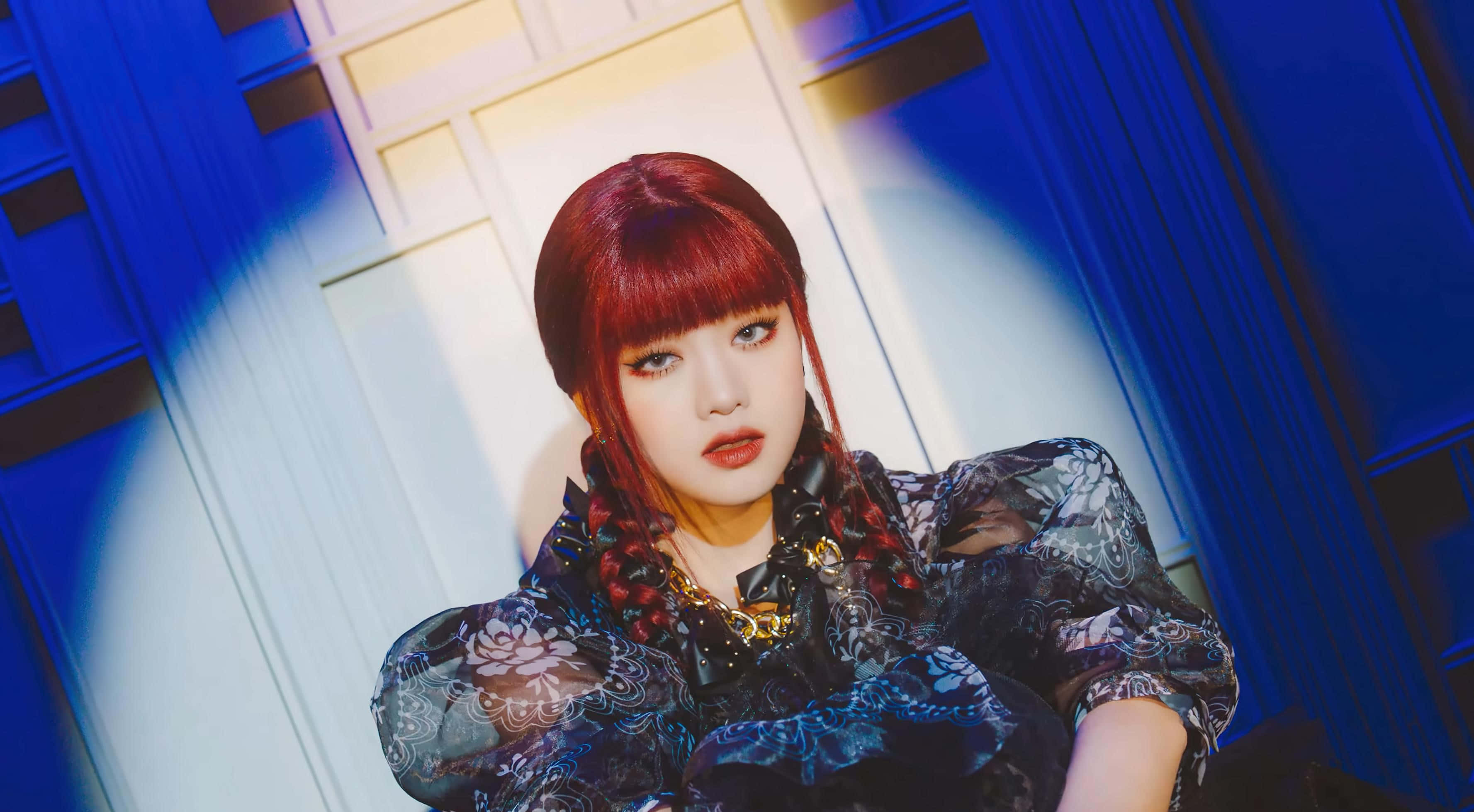 K-pop 桌布 壁紙 — 一位紅髮辮子女性穿著深色花卉連衣裙，在戲劇性的藍白燈光下。