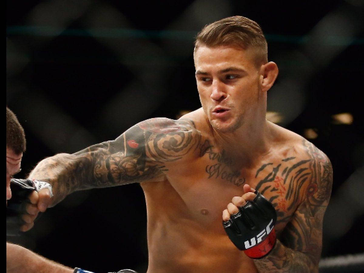 MMA 桌布 壁紙 — 一位紋身MMA拳手戴著UFC手套，在八角籠中出拳，背景燈光模糊。