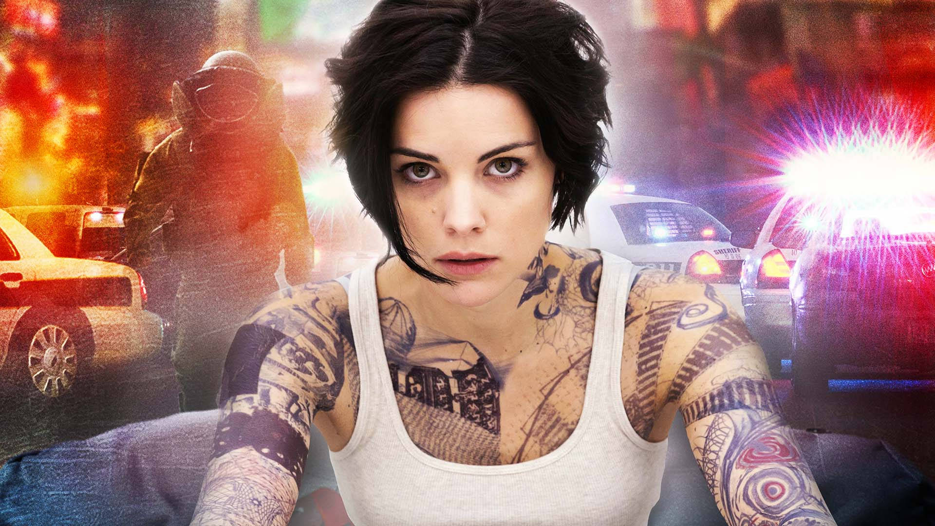 Celebrity 桌布 壁紙 — 一位紋身女子強烈地凝視鏡頭，身後警車和爆炸模糊地出現在混亂的城市場景中。