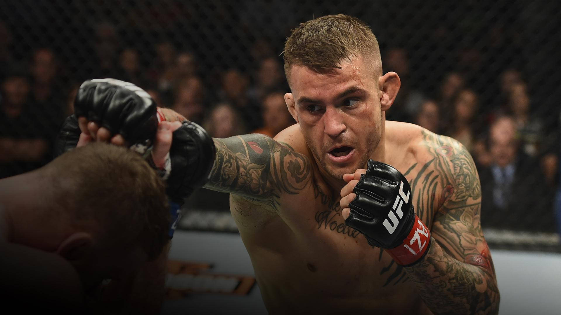 MMA 桌布 壁紙 — 一位紋身的MMA拳手在UFC八角籠內打出強力一拳，背景是模糊的人群。