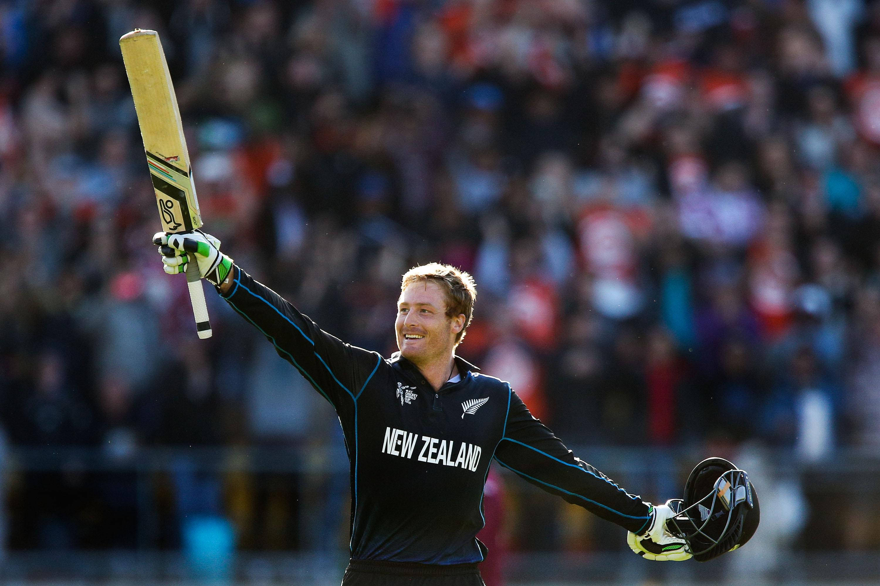 martin guptill 桌布 壁紙 — 一位紐西蘭板球運動員在陽光明媚的日間比賽中，勝利地高舉球棒和頭盔慶祝。