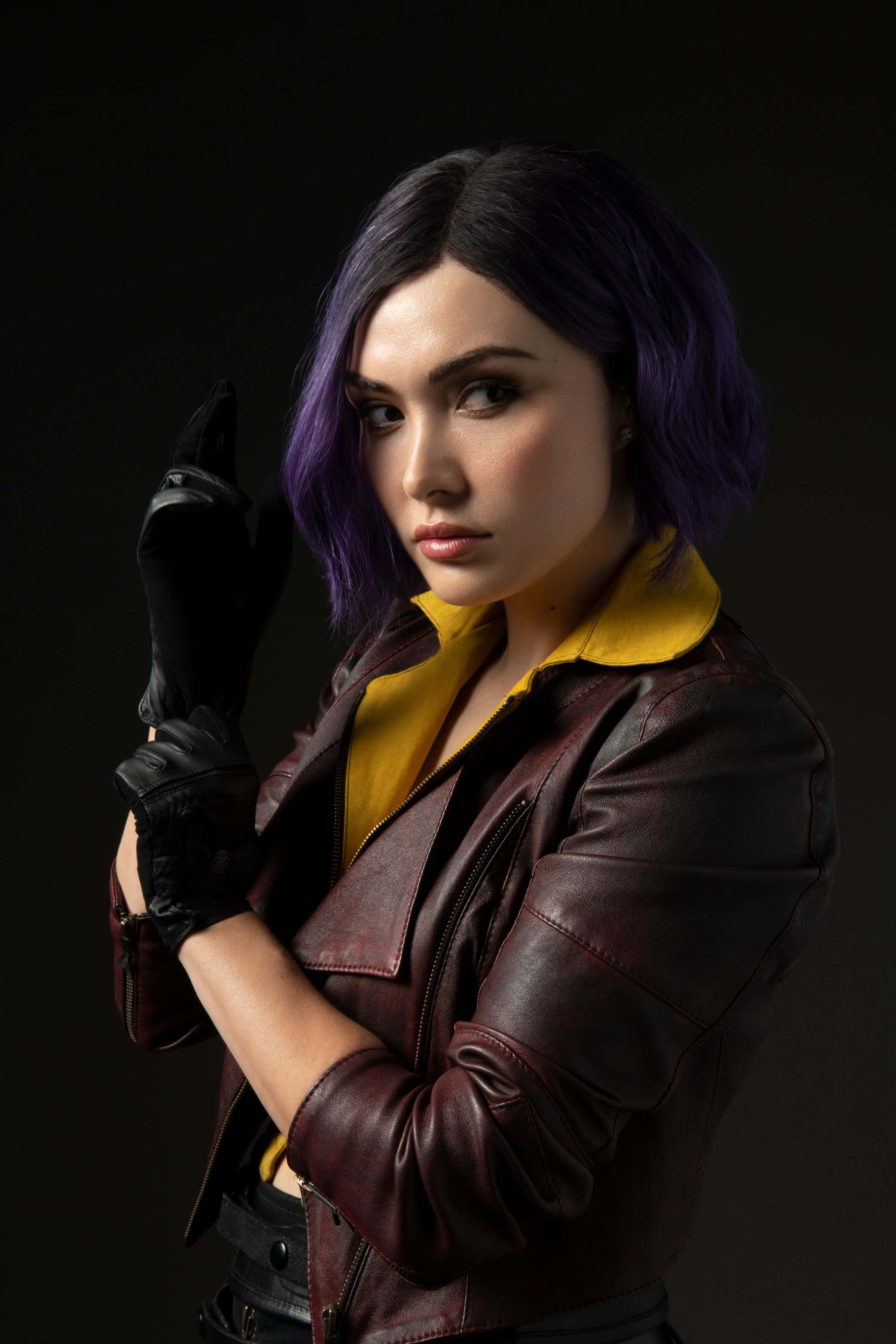 Faye Valentine 桌布 壁紙 — 一位紫色頭髮的女性，在深色背景前穿著一件黃色領的棕色皮夾克和黑色手套。