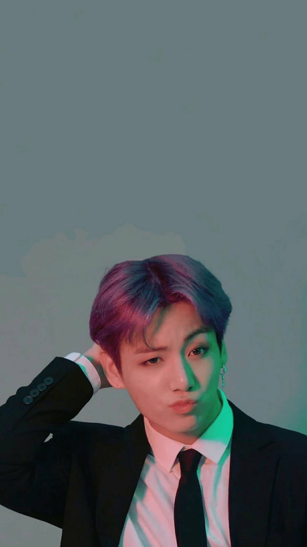 BTS 桌布 壁紙 — 一位紫藍色頭髮的年輕男子穿著黑色西裝，在帶有霓虹燈光點綴的柔和灰色背景前擺姿勢。
