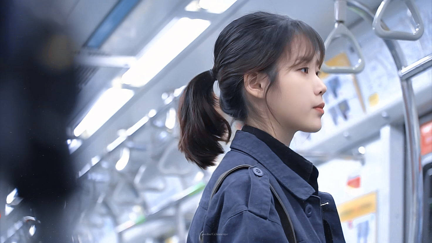 火車 桌布 壁紙 — 一位紮馬尾的年輕女性從光線明亮的地鐵車廂內若有所思地凝視著。