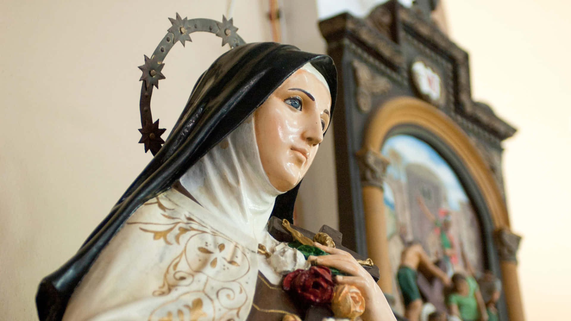 Mother Mary 桌布 壁紙 — 一位聖人手持玫瑰、頭頂荊棘冠冕的寧靜宗教雕像特寫。