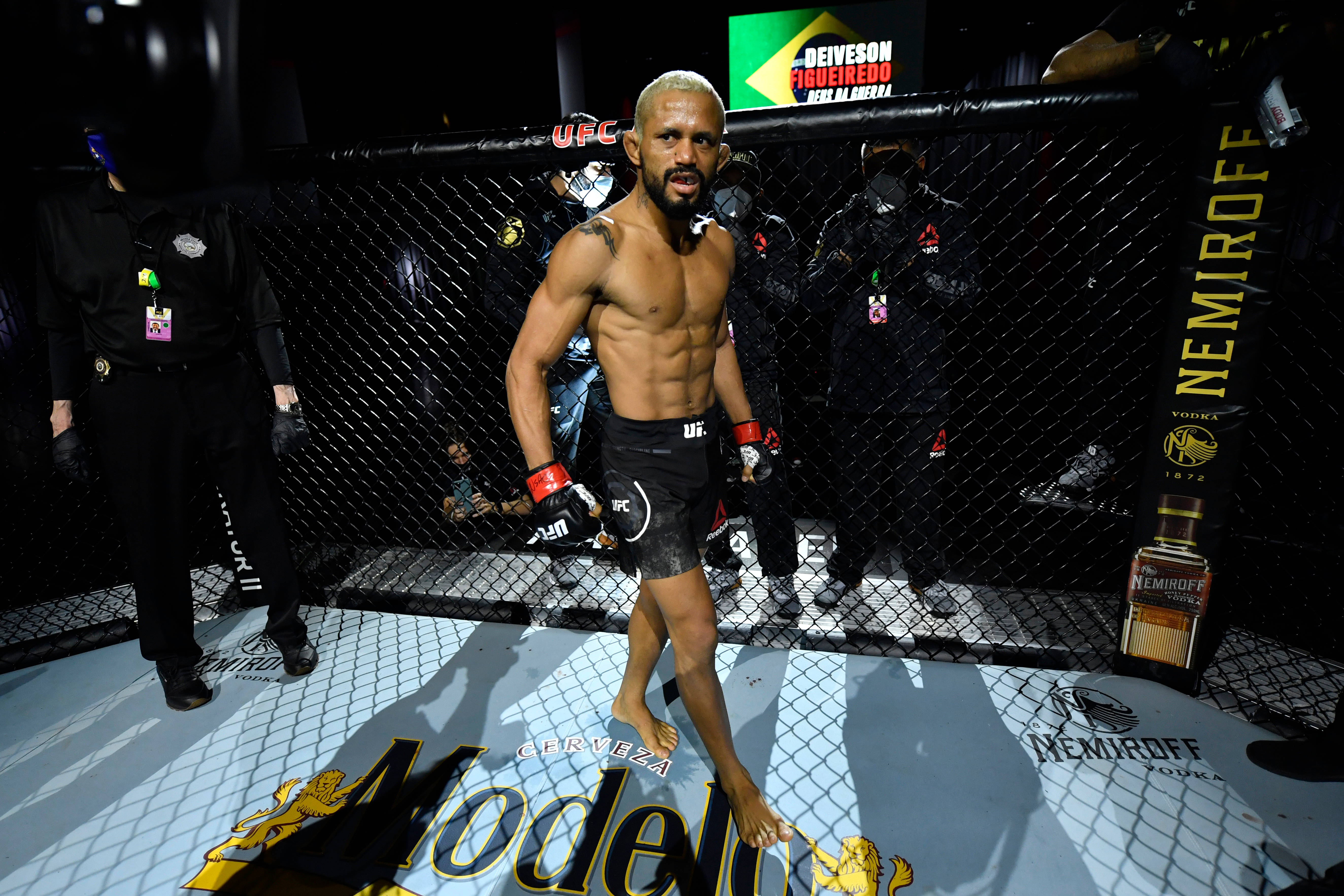UFC 桌布 壁紙 — 一位肌肉發達、剃光頭、留鬍子的UFC拳手，在明亮的場館燈光下自信地走進八角籠。