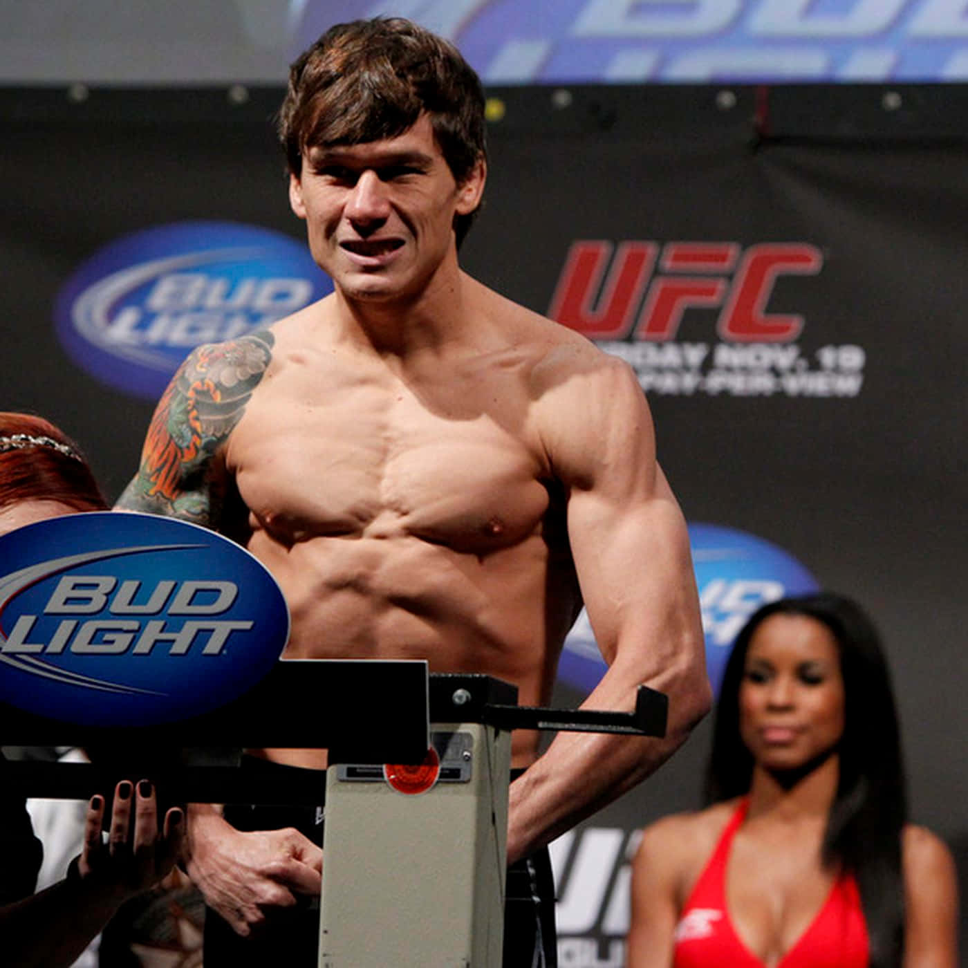 UFC 桌布 壁紙 — 一位肌肉發達、手臂有刺青的UFC拳手，在Bud Light和UFC品牌的過磅活動中赤裸上身站在磅秤上。