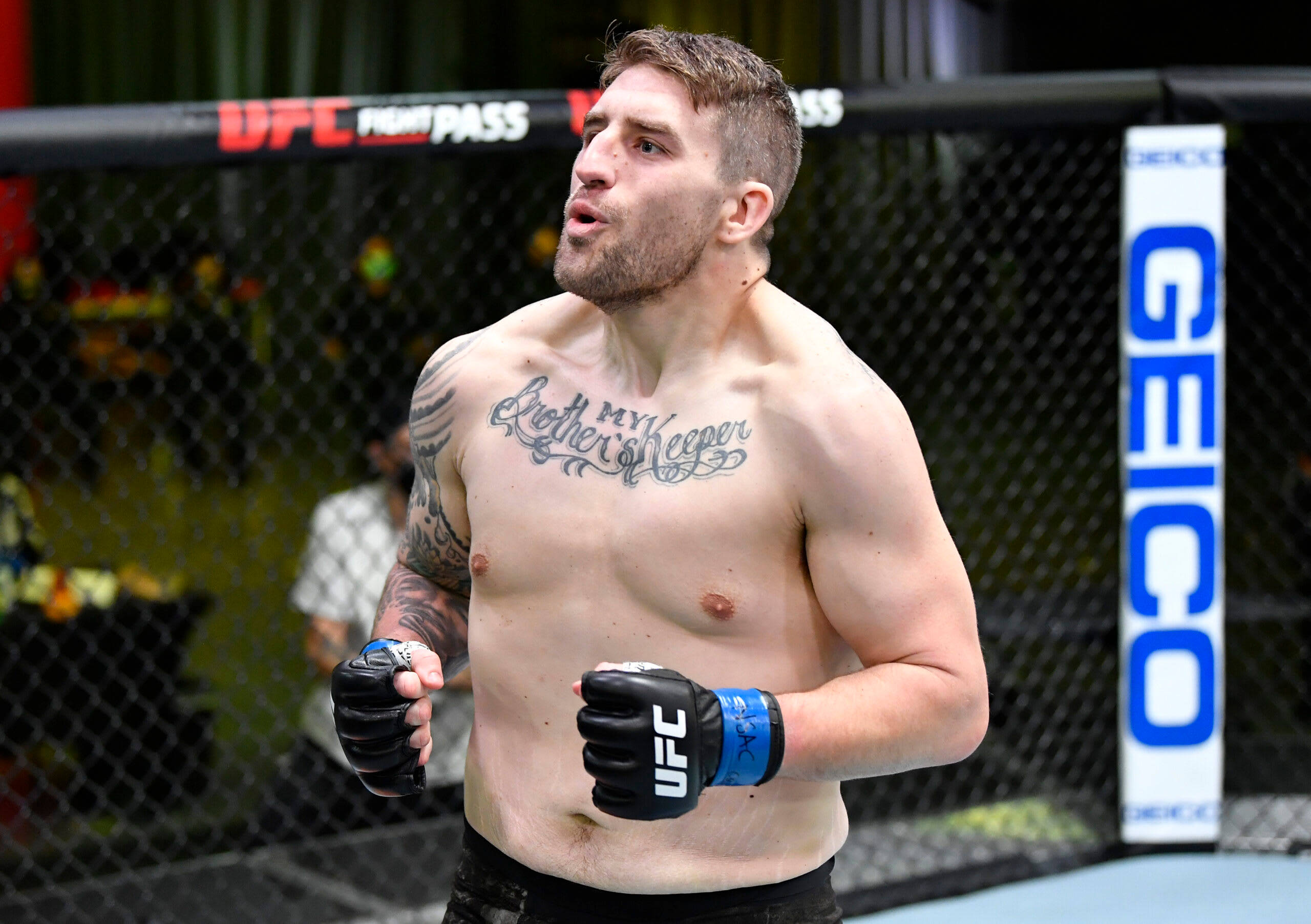 UFC 桌布 壁紙 — 一位肌肉發達、有刺青的UFC拳擊手戴著手套和黑色短褲站在八角籠內。