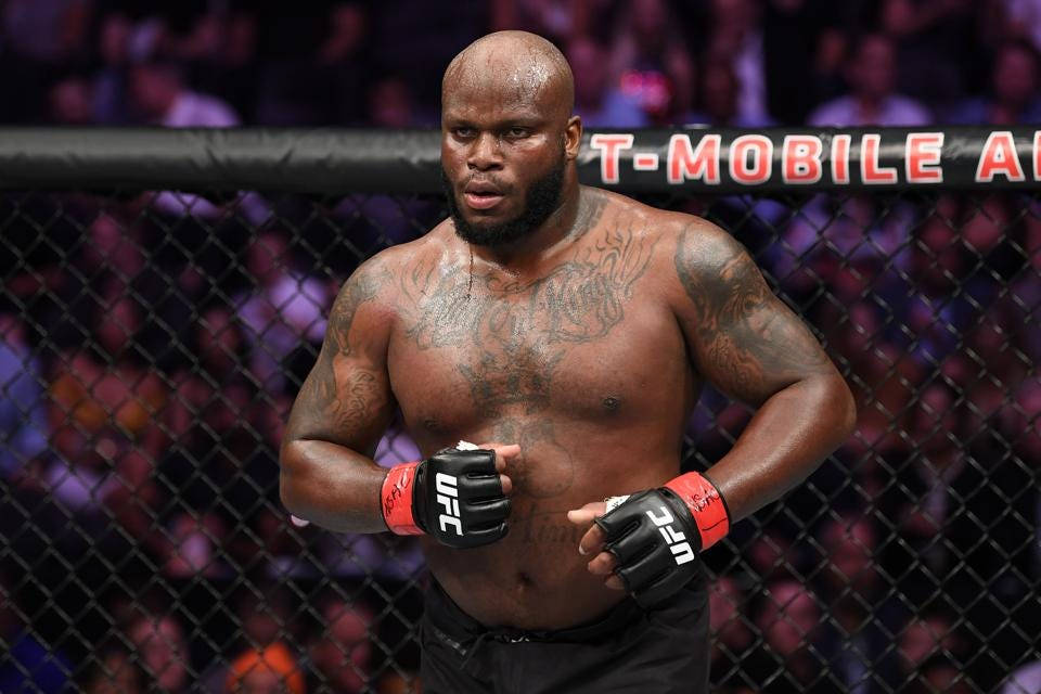 UFC 桌布 壁紙 — 一位肌肉發達、有刺青的拳手，帶著專注的表情，戴著紅黑手套，站在UFC八角籠內。