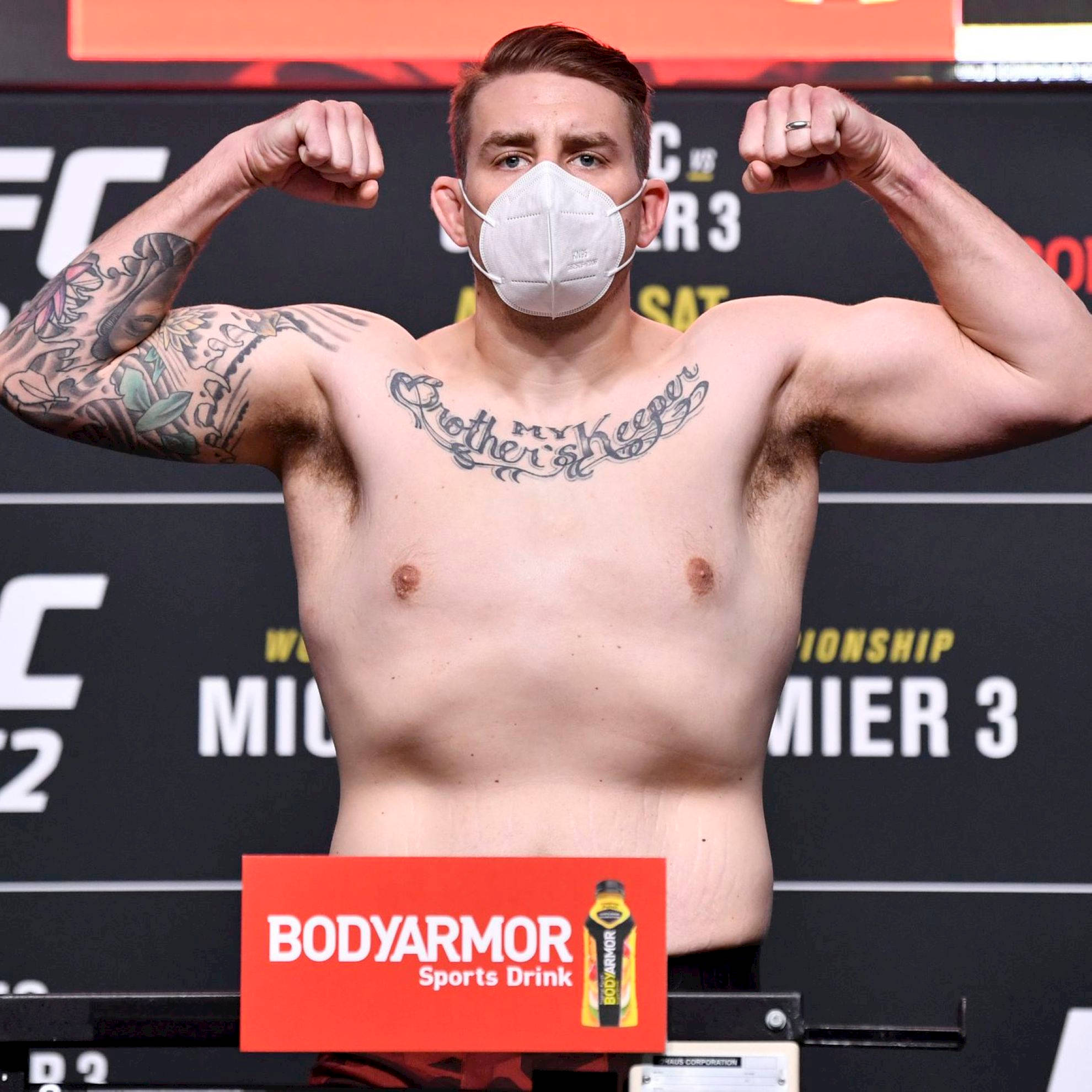 MMA 桌布 壁紙 — 一位肌肉發達、有刺青的拳手在UFC稱重活動中戴著口罩彎曲手臂。