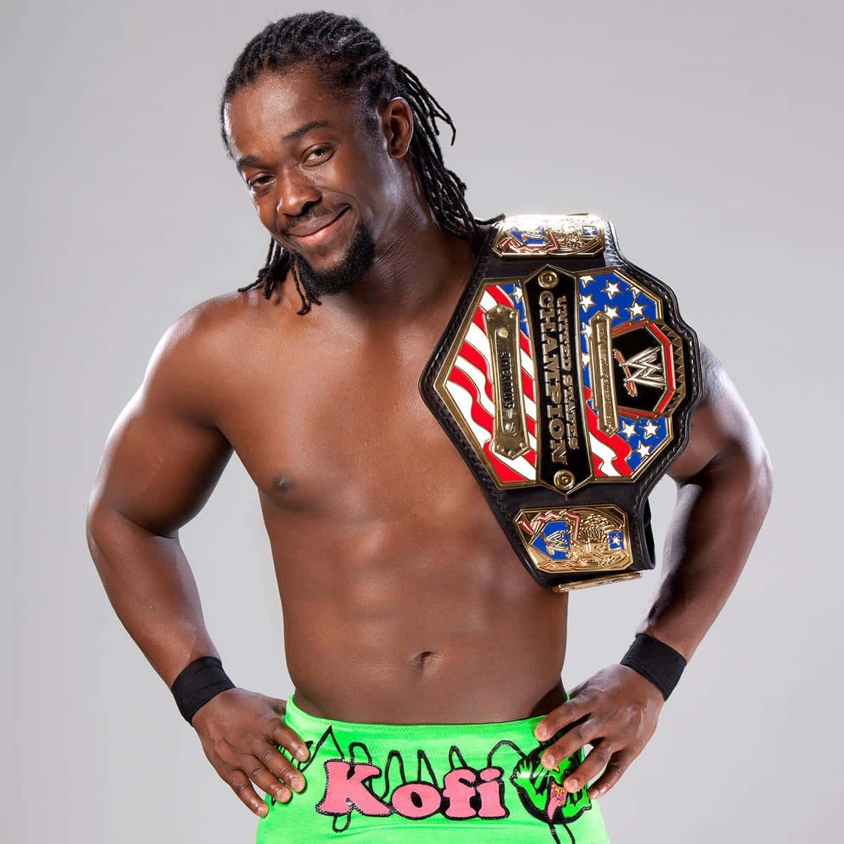 WWE 桌布 壁紙 — 一位肌肉發達、留著辮子的摔角手，在純灰色背景前自信地微笑，肩上掛著冠軍腰帶擺姿勢。