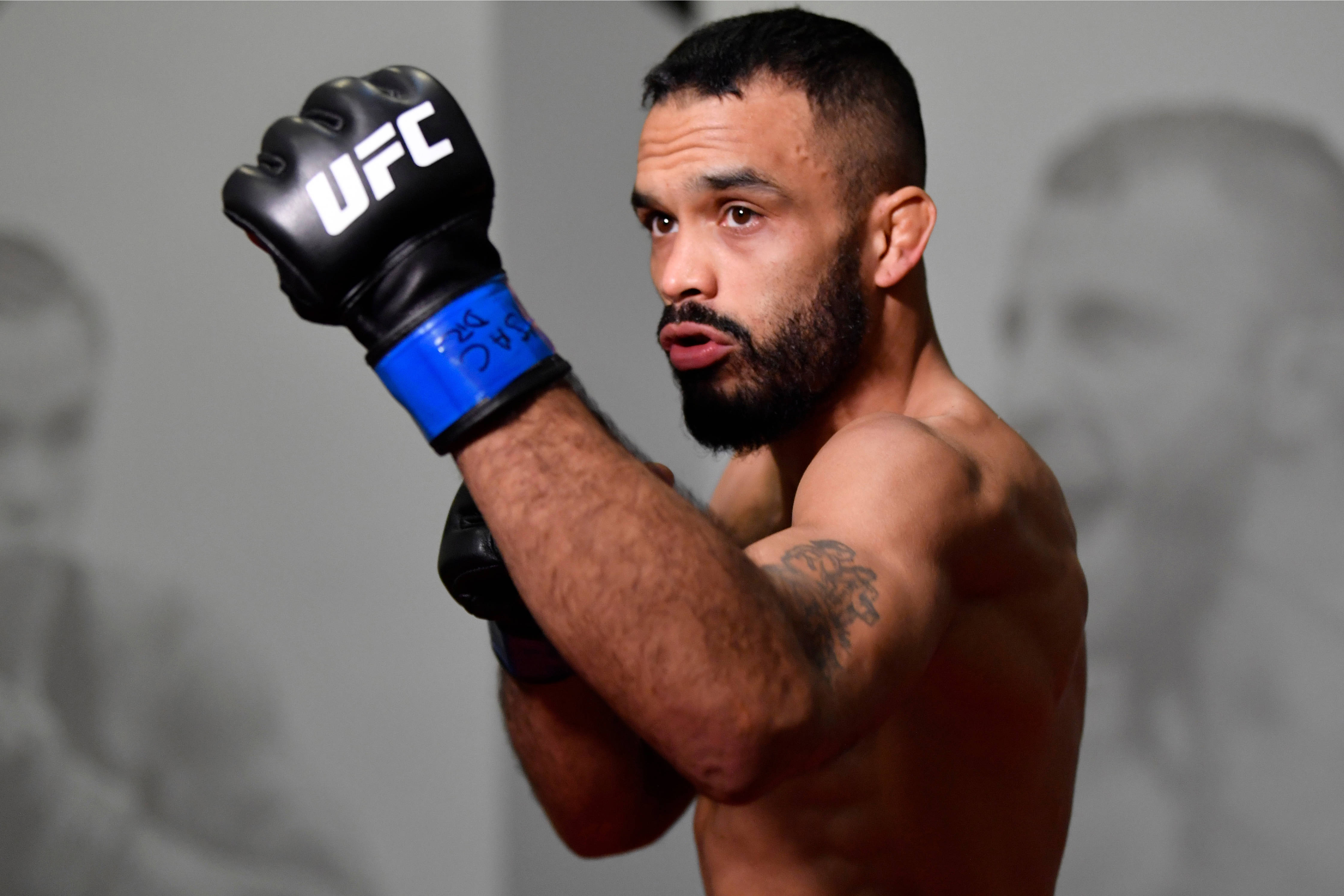 UFC 桌布 壁紙 — 一位肌肉發達、留鬍子、手臂有刺青的UFC拳手，戴著黑色手套，在灰色背景前擺出專注姿勢。