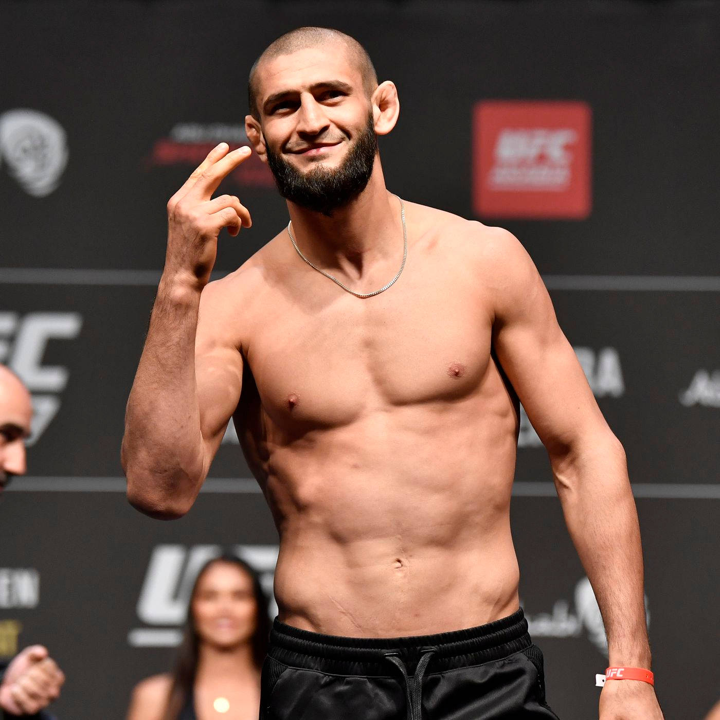 Athletic 桌布 壁紙 — 一位肌肉發達、留鬍子的UFC拳手在稱重活動中自信地微笑，做出和平手勢。