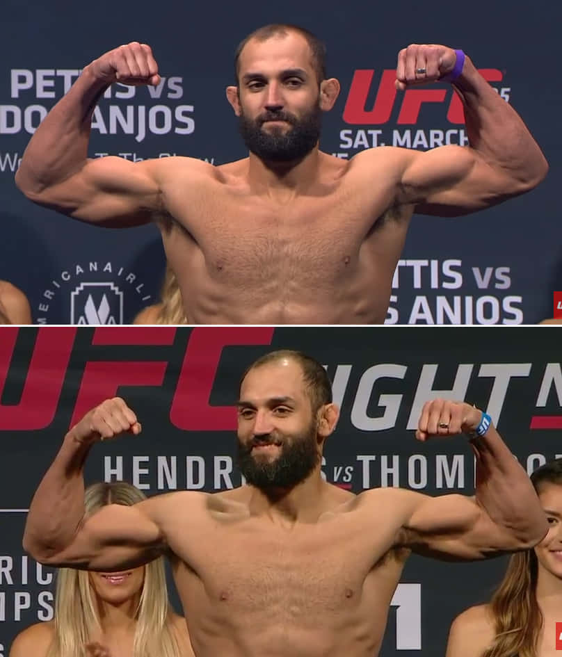 UFC 桌布 壁紙 — 一位肌肉發達、留鬍子的拳手在UFC稱重活動中彎曲手臂，身後有宣傳橫幅。