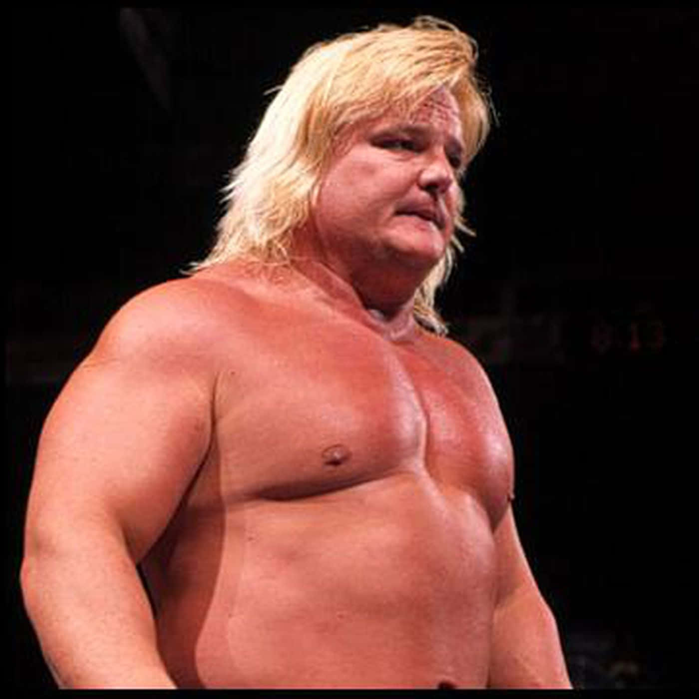 WWE 桌布 壁紙 — 一位肌肉發達、長金髮的摔角手在黑暗背景下，赤裸上身站在明亮的舞台燈光下。