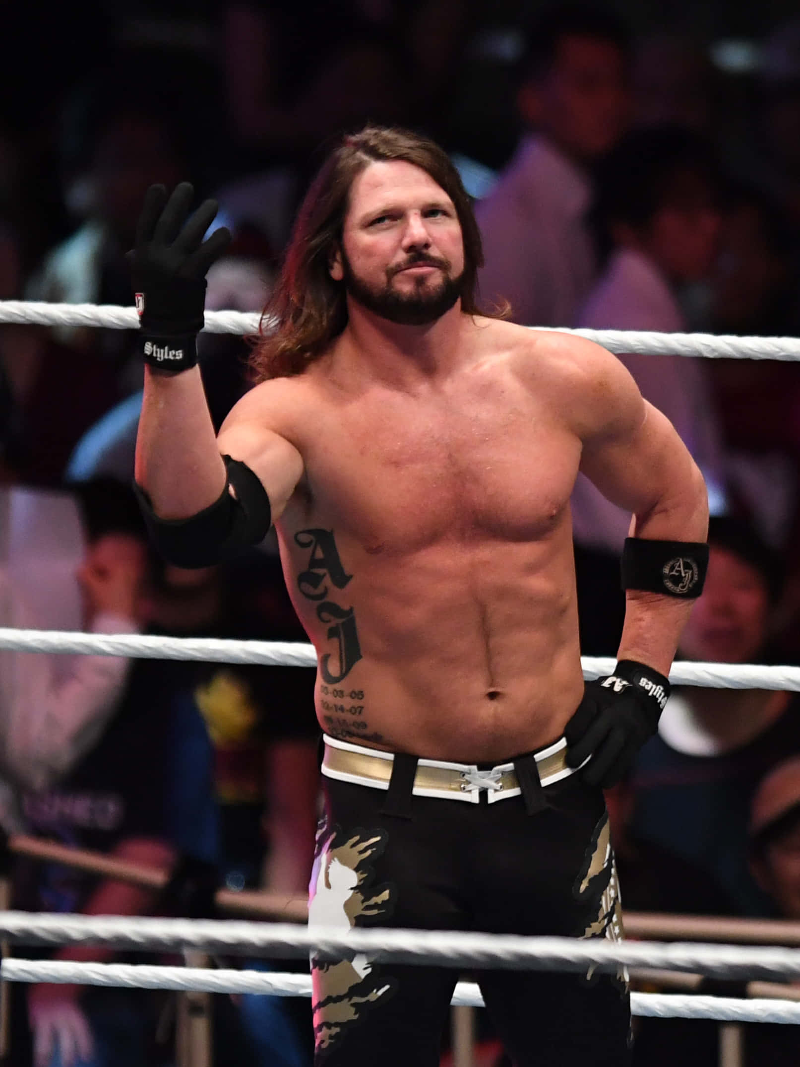 WWE 桌布 壁紙 — 一位肌肉發達、長髮且有刺青的摔角手在摔角場內向人群揮手。