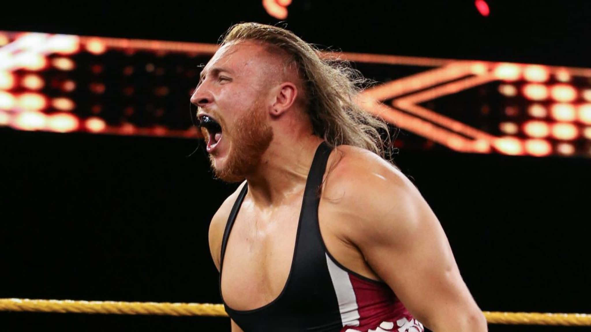 screaming 桌布 壁紙 — 一位肌肉發達、長髮鬍鬚的摔角手在明亮的場館燈光下於擂台上咆哮。