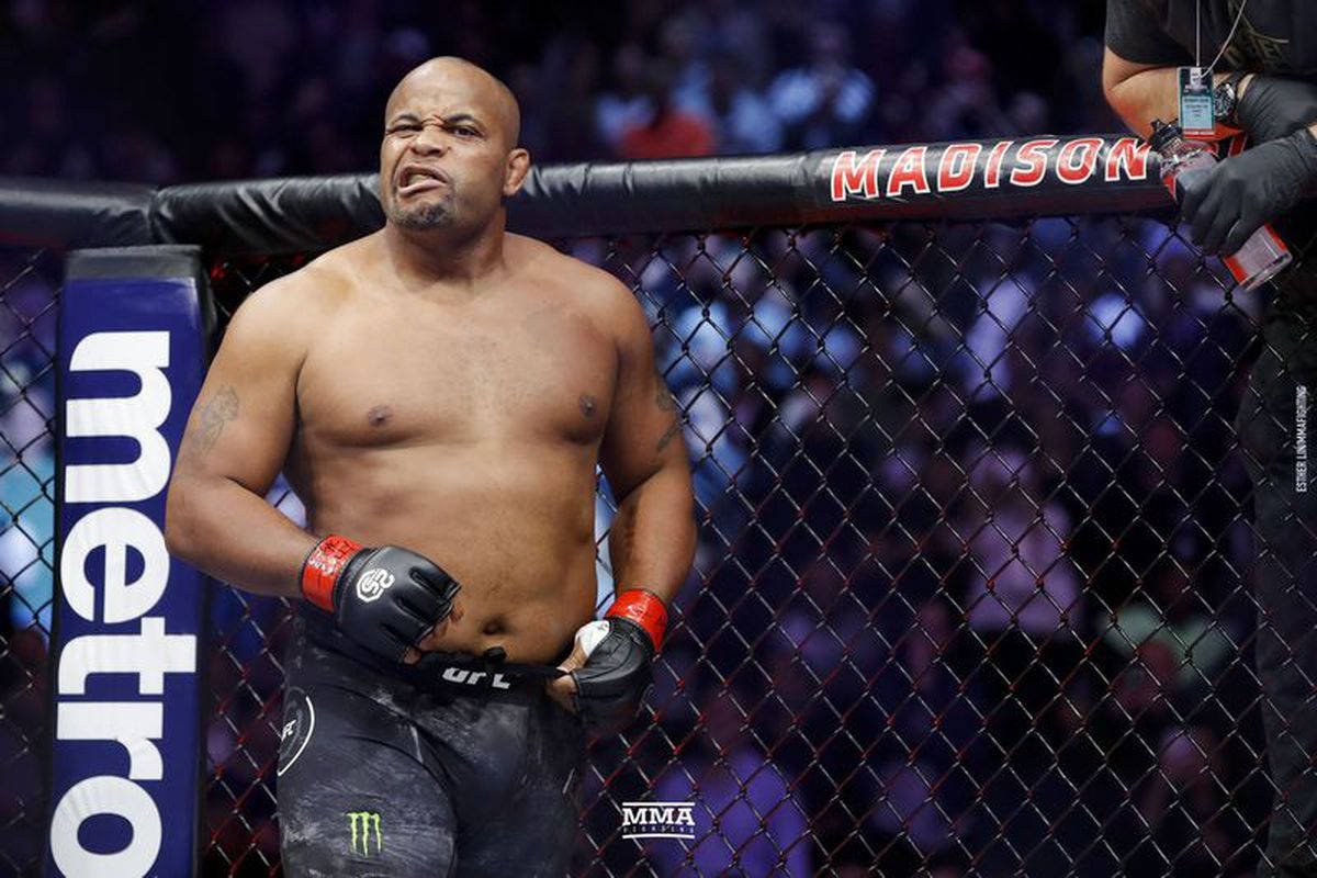 UFC 桌布 壁紙 — 一位肌肉發達的MMA拳手在明亮的場館燈光下，於籠中比賽時面露苦相。