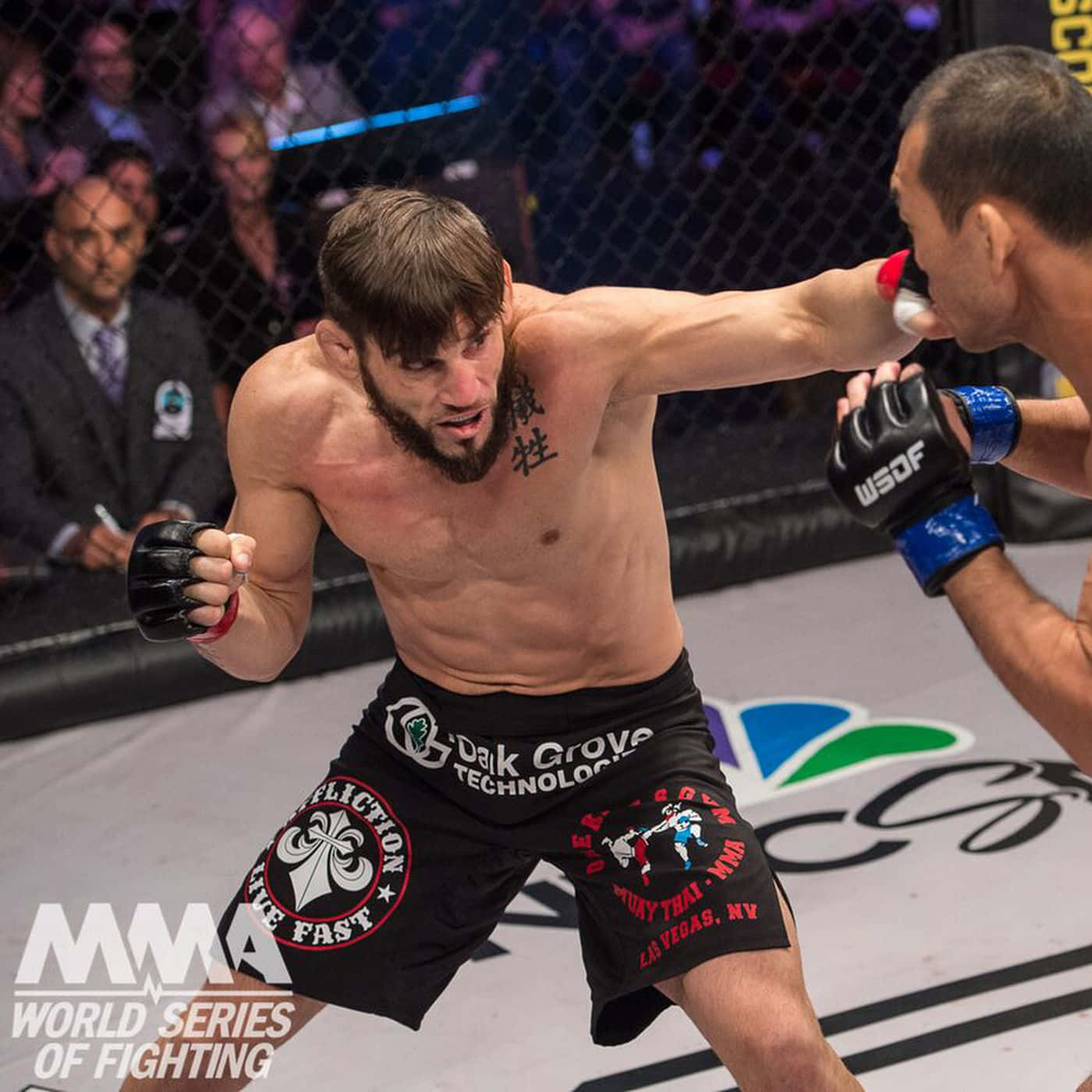 UFC 桌布 壁紙 — 一位肌肉發達的MMA拳手在明亮的八角籠內，於一場競技比賽中向對手打出強力一拳。