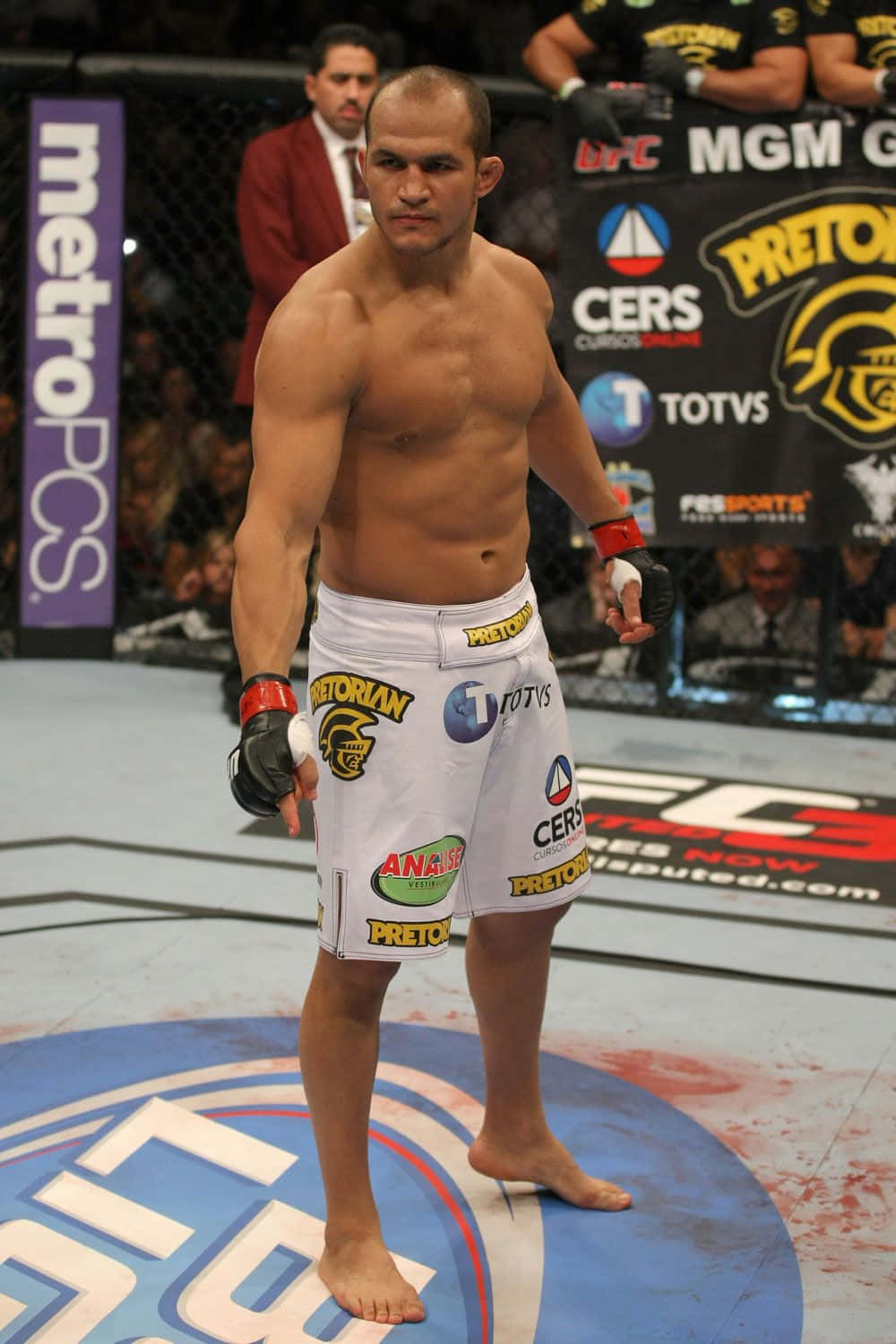 martial arts 桌布 壁紙 — 一位肌肉發達的MMA拳手赤腳站在UFC八角籠中央，墊上有贊助商標誌和血跡。