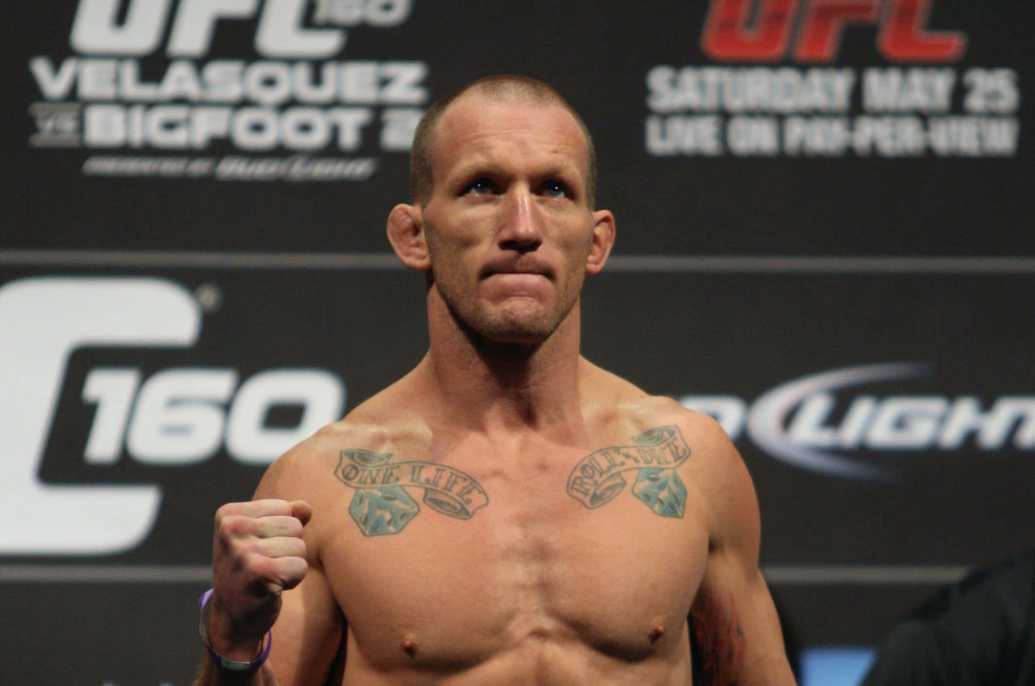 Fight 桌布 壁紙 — 一位肌肉發達的UFC拳手，胸口有刺青，在稱重活動中赤裸上身，神情專注。