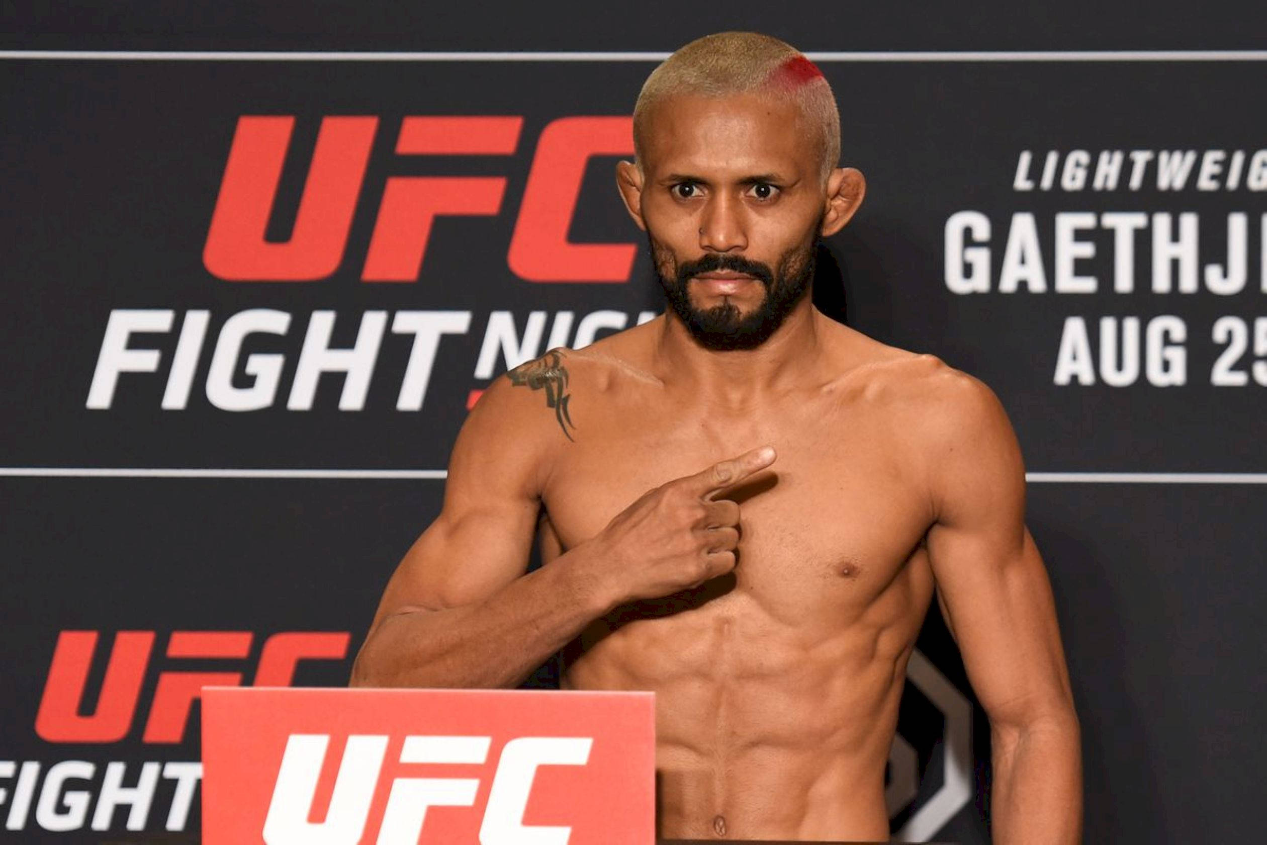 MMA 桌布 壁紙 — 一位肌肉發達的UFC拳手，頭髮上有一道紅色條紋，在稱重活動中指向自己的胸口。