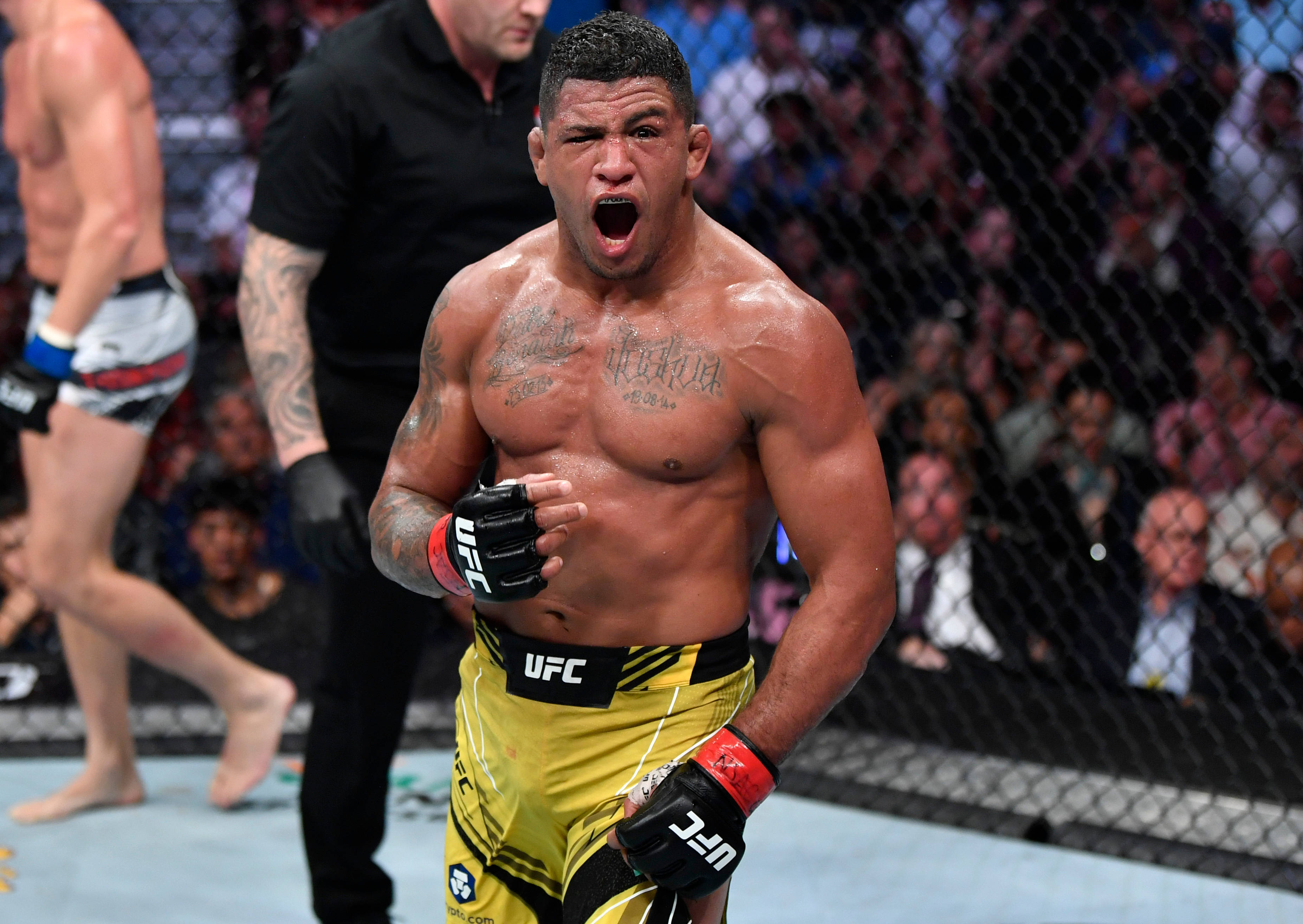 UFC 桌布 壁紙 — 一位肌肉發達的UFC拳手在八角籠內勝利咆哮，背景有粉絲歡呼。