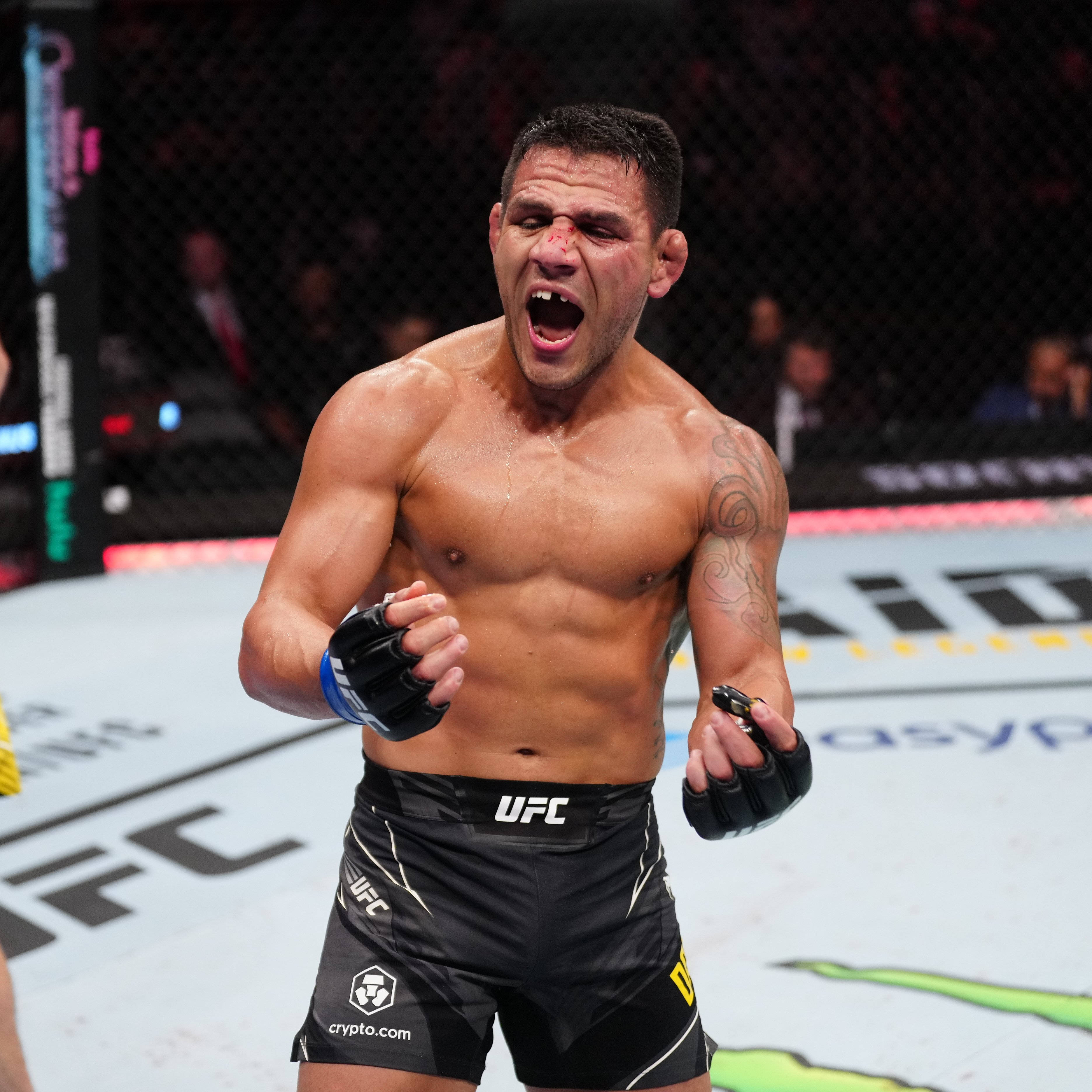喜悅 桌布 壁紙 — 一位肌肉發達的UFC拳手在八角籠內咆哮勝利，臉上帶血，拳頭緊握。