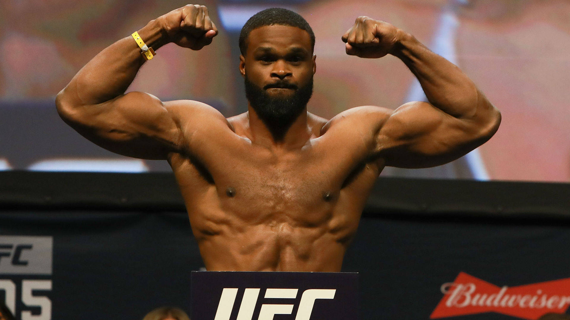Tyron Woodley 桌布 壁紙 — 一位肌肉發達的UFC拳手在明亮的場館燈光下，於稱重活動中赤裸上身，在體重磅上彎曲手臂。