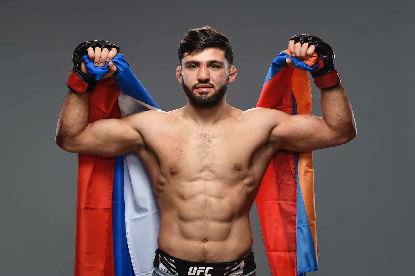 MMA 桌布 壁紙 — 一位肌肉發達的UFC拳手在灰色工作室背景前，自豪地將俄羅斯國旗披在肩上。