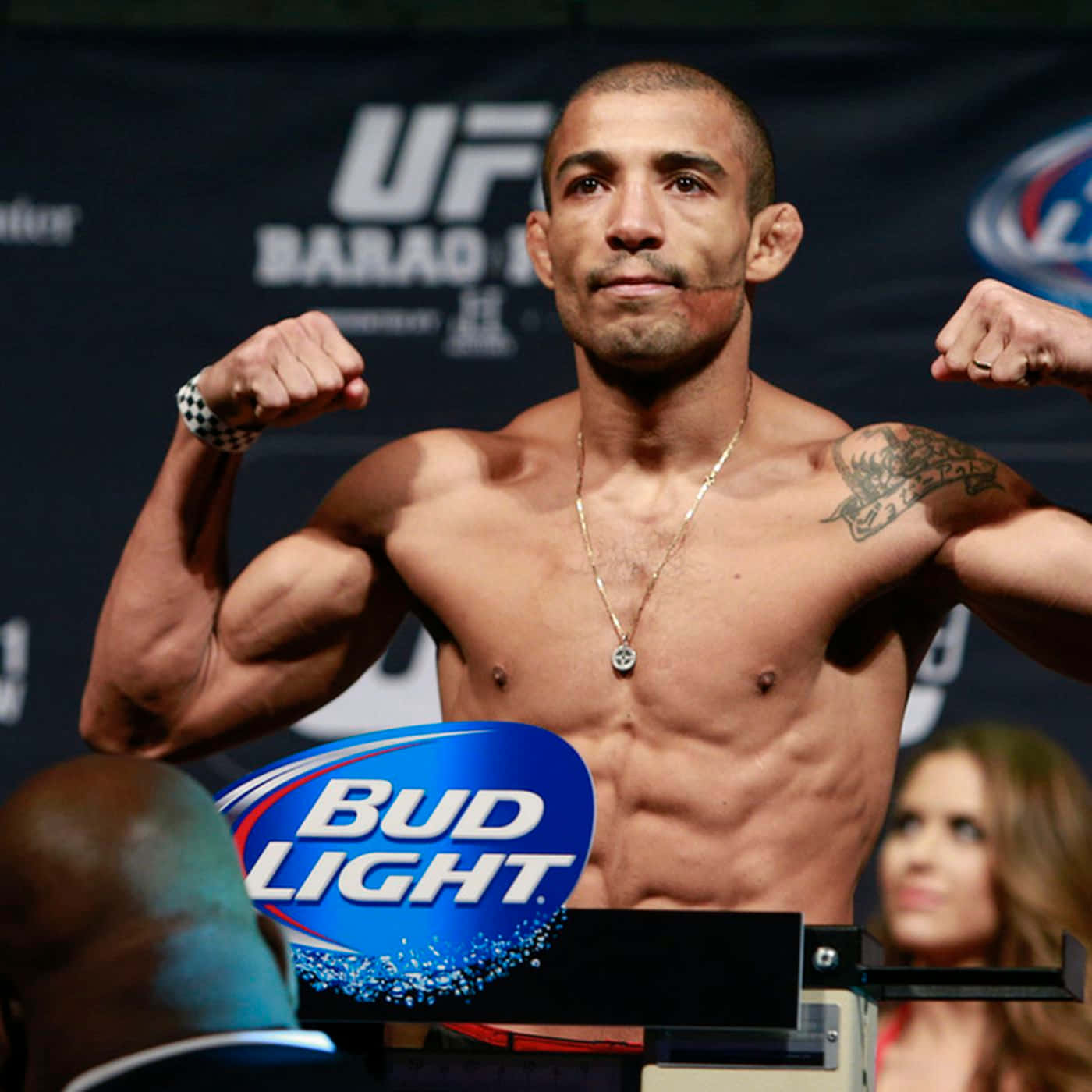 UFC 桌布 壁紙 — 一位肌肉發達的UFC拳手在秤重活動中於體重磅上屈起手臂，Bud Light標誌清晰可見。