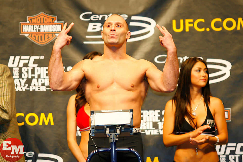 MMA 桌布 壁紙 — 一位肌肉發達的UFC拳手在稱重活動中赤裸上身站在體重磅上，雙手做出和平手勢。