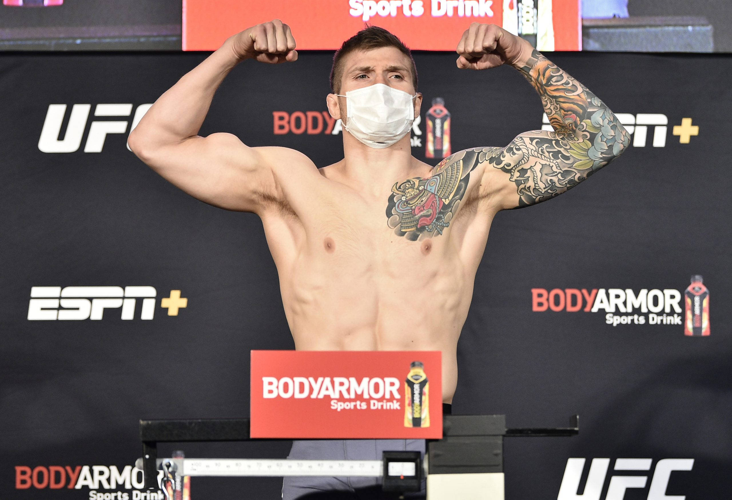 MMA 桌布 壁紙 — 一位肌肉發達的UFC拳手在稱重活動中戴著口罩，展示他刺青的手臂。