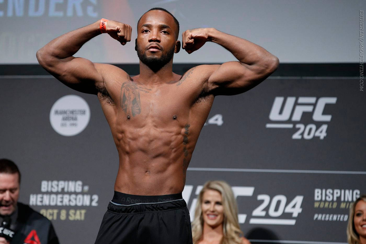 MMA 桌布 壁紙 — 一位肌肉發達的UFC拳手在背後有「UFC 204」品牌的過磅活動中，在磅秤上屈起雙臂。