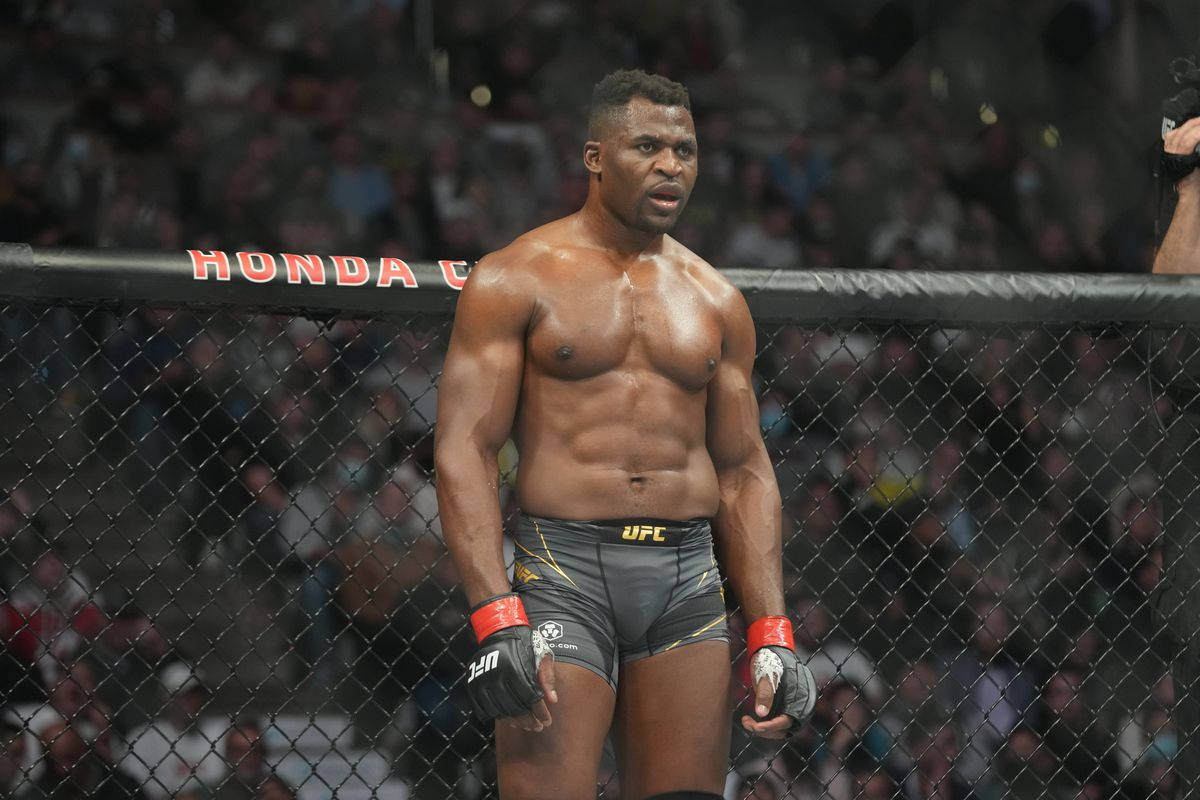 Athletic 桌布 壁紙 — 一位肌肉發達的UFC拳手站在八角籠內，神情專注，周圍飄落著五彩紙屑。