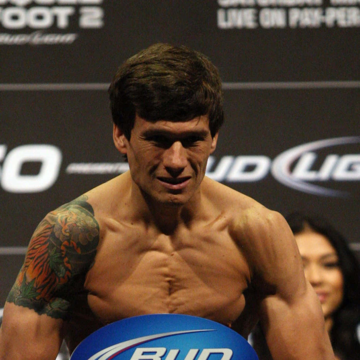 UFC 桌布 壁紙 — 一位肌肉發達的戰士，身上有老虎刺青，在稱重活動中專注地凝視鏡頭。