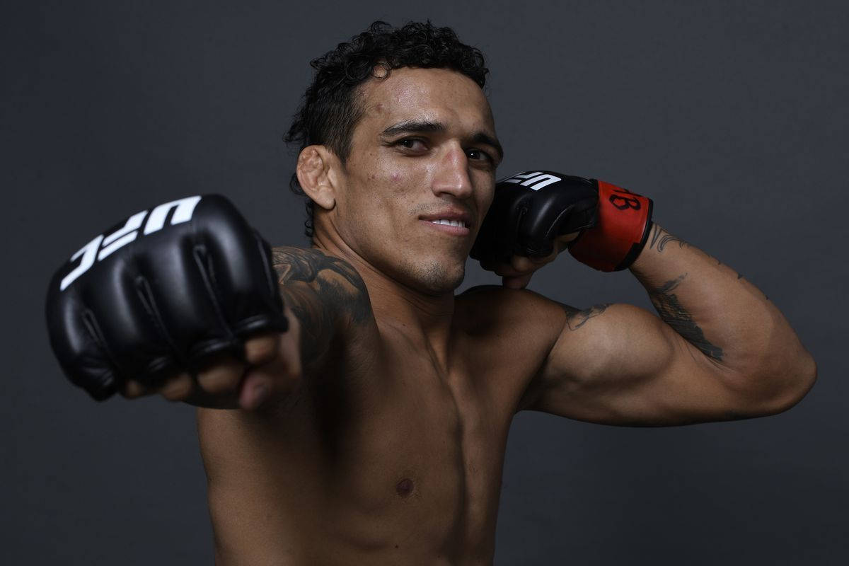 MMA 桌布 壁紙 — 一位肌肉發達的戰士戴上黑色UFC手套，在黑暗的攝影棚背景下擺出自信姿勢。