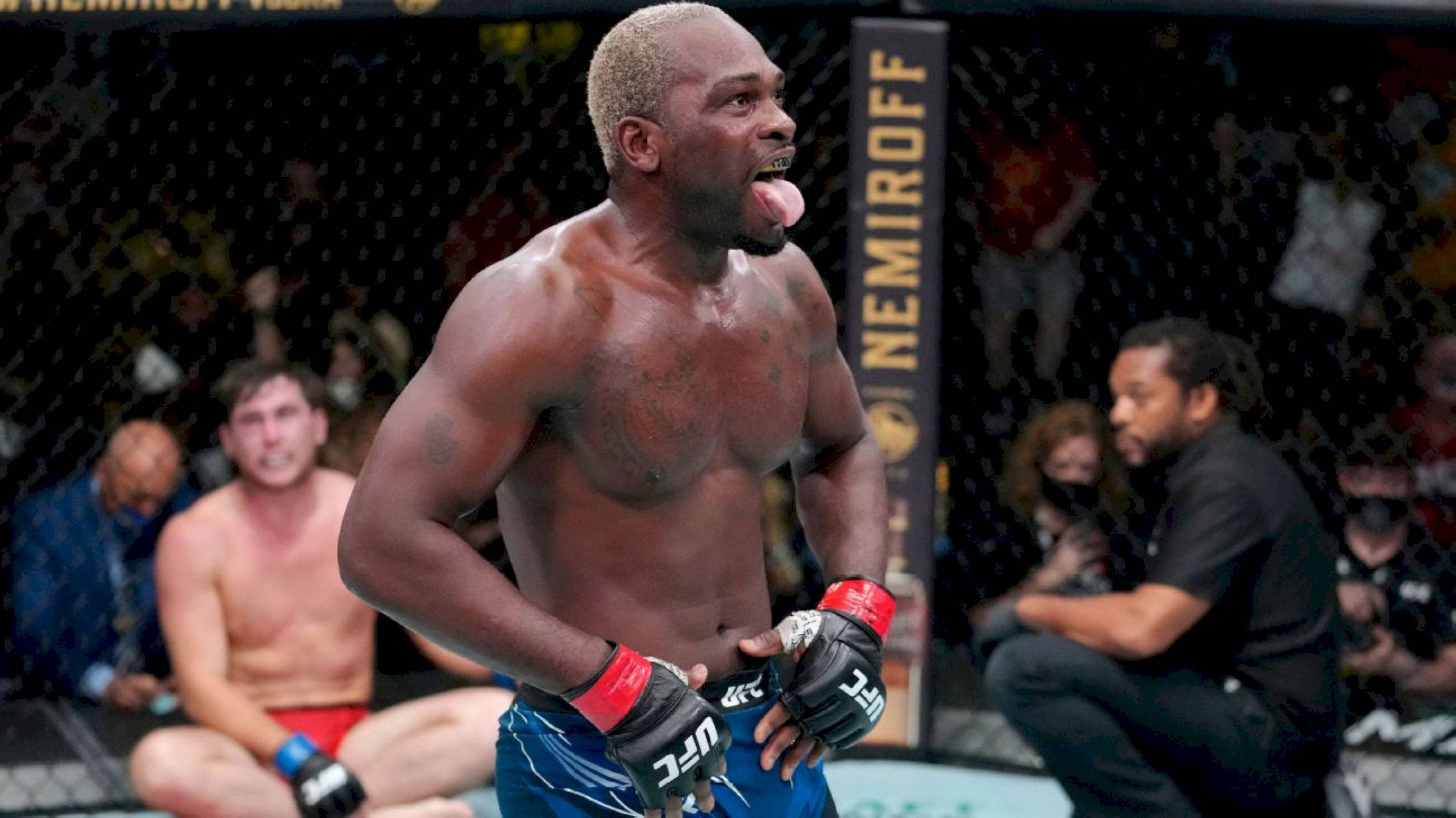 Champion 桌布 壁紙 — 一位肌肉發達的戰士穿著藍色短褲和UFC手套，在濕滑的八角籠內伸出舌頭慶祝勝利。