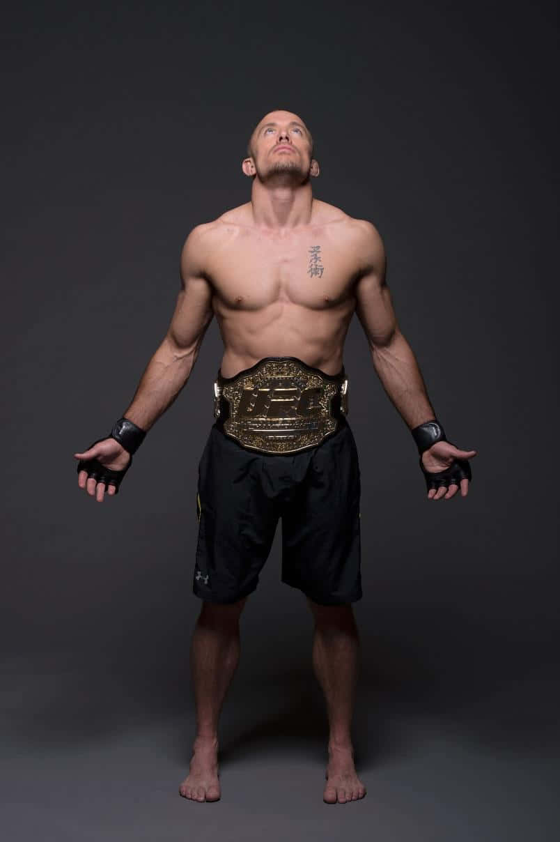 martial arts 桌布 壁紙 — 一位肌肉發達的戰士穿著黑色短褲和手套，赤腳站立，雙臂伸展，腰間繫著冠軍腰帶，背景是深色攝影棚。