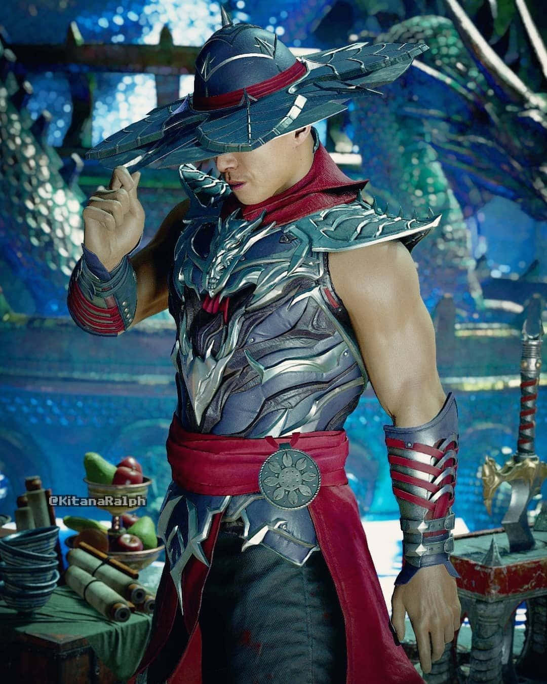 Mortal Kombat Kung Lao 桌布 壁紙 — 一位肌肉發達的戰士身穿華麗的銀色和紅色盔甲，戴著寬邊帽，自信地站在充滿活力的藍色神秘環境中。