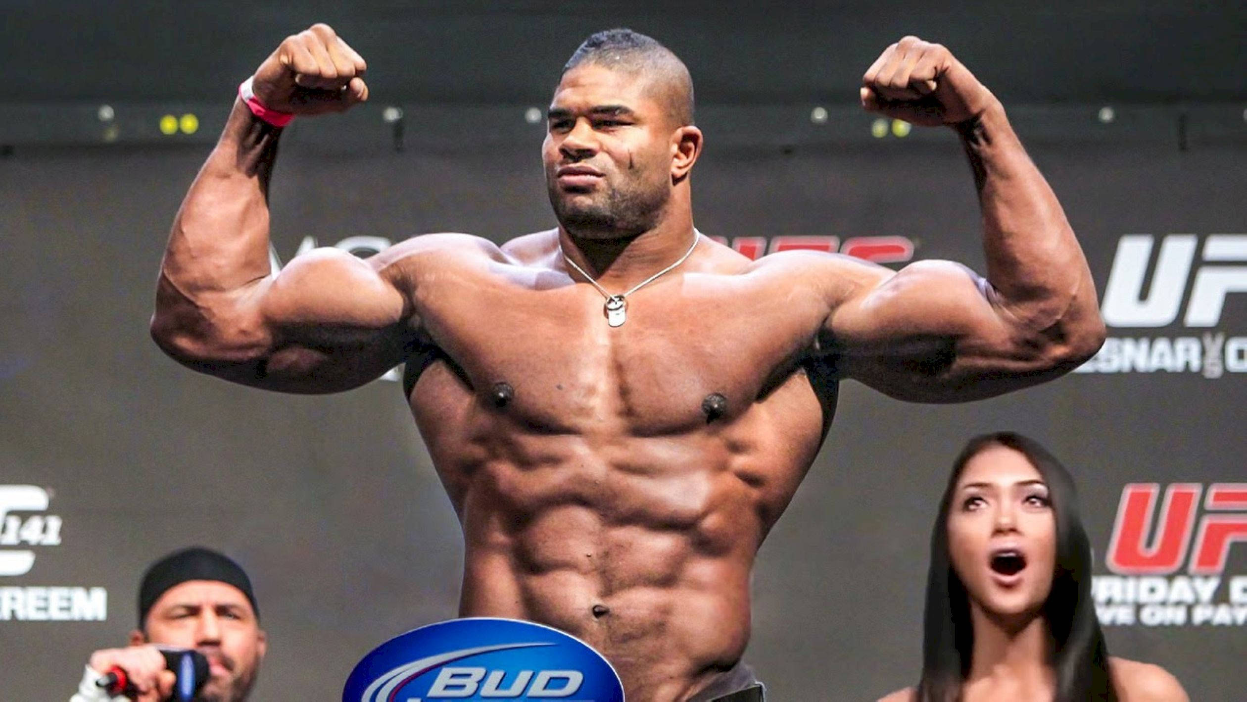 UFC 桌布 壁紙 — 一位肌肉發達的拳手在UFC體重磅上彎曲手臂，旁邊有一位驚訝的女性。