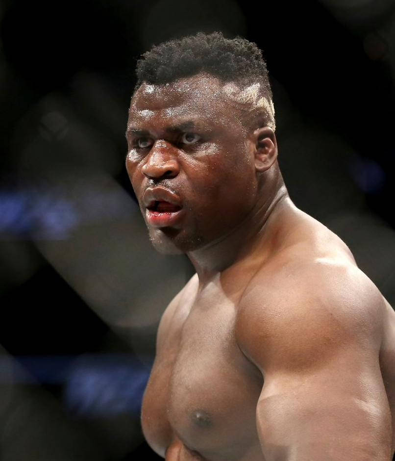 MMA 桌布 壁紙 — 一位肌肉發達的拳手在明亮的場館燈光下進行搏擊比賽，汗水在皮膚上閃閃發光，眼神專注。