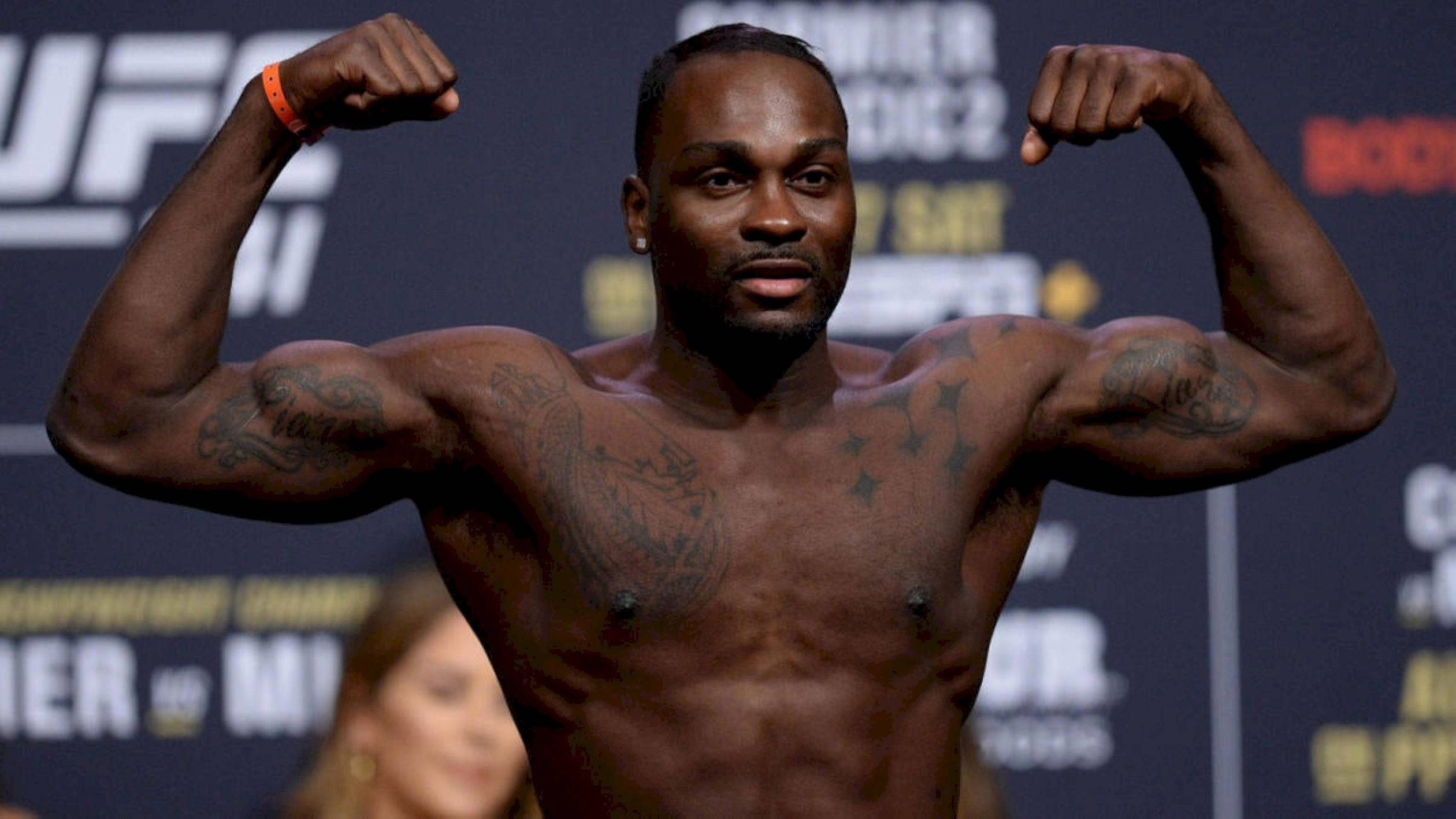 Athletic 桌布 壁紙 — 一位肌肉發達的拳手在明亮的攝影棚燈光下，於UFC稱重活動中繃緊他帶有刺青的手臂。