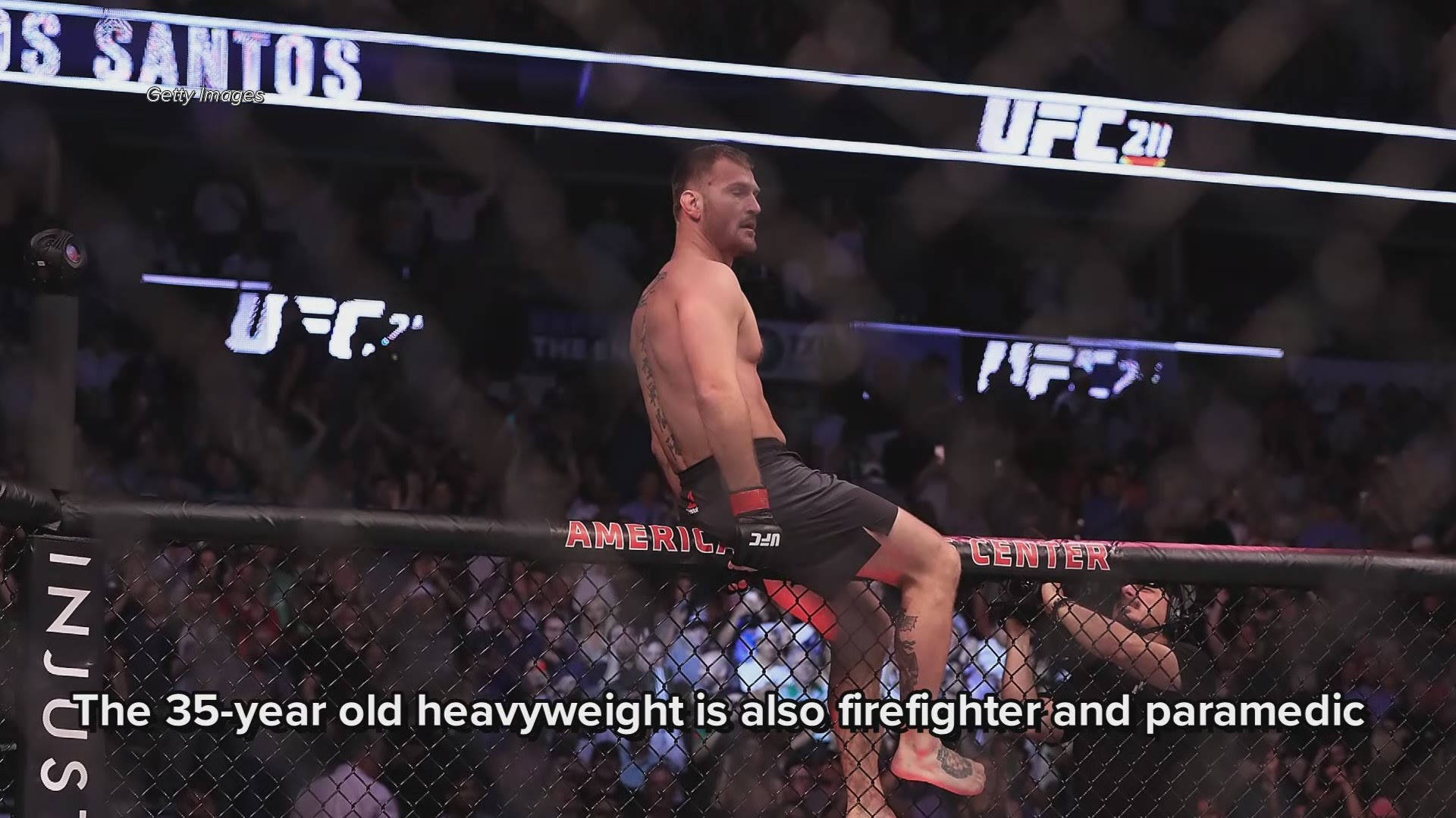 UFC 桌布 壁紙 — 一位肌肉發達的拳手坐在UFC 211賽事的八角籠圍欄頂部，背景可見人群和品牌標誌。