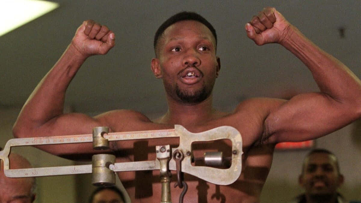Boxing 桌布 壁紙 — 一位肌肉發達的拳擊手在健身房的復古磅秤上勝利地彎曲手臂。