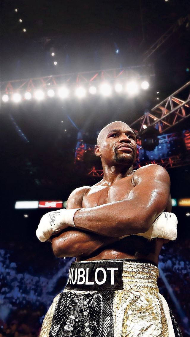 Boxing 桌布 壁紙 — 一位肌肉發達的拳擊手在明亮的競技場燈光下自信地交叉雙臂站在擂台上。