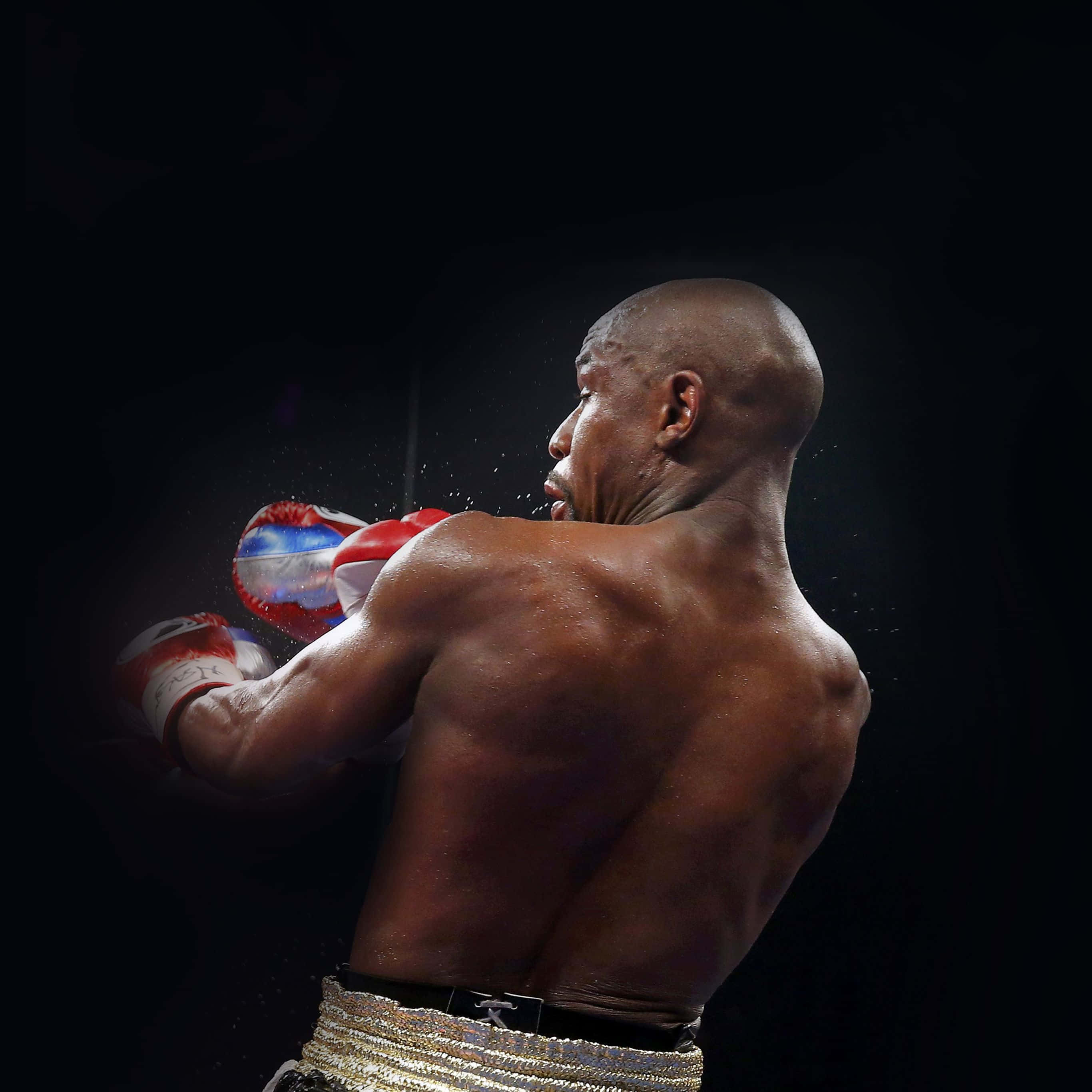 Boxing 桌布 壁紙 — 一位肌肉發達的拳擊手戴著紅白手套，在黑暗背景下打出強力一拳，汗水以慢動作飛濺。